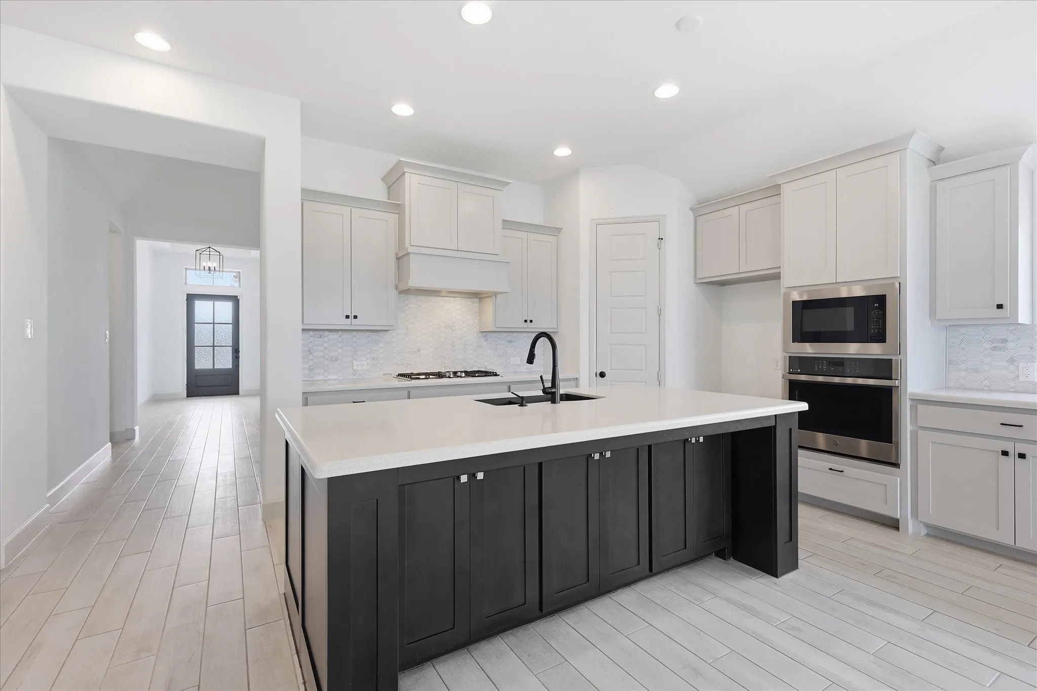 Modern kitchen featuring a central island with dark cabinetry, integrated sink, and white countertop