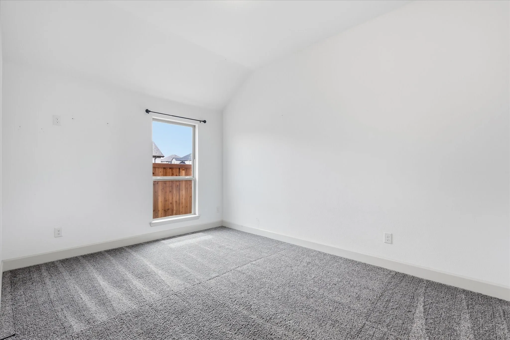Room featuring vaulted ceilings and neutral-toned carpeting