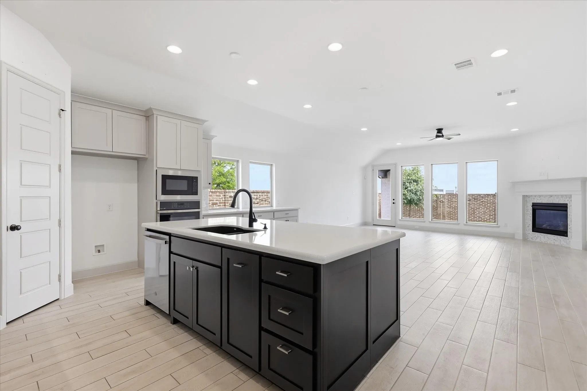 Kitchen island featuring a black sink and matte black faucet, complemented by light wood-finish flooring