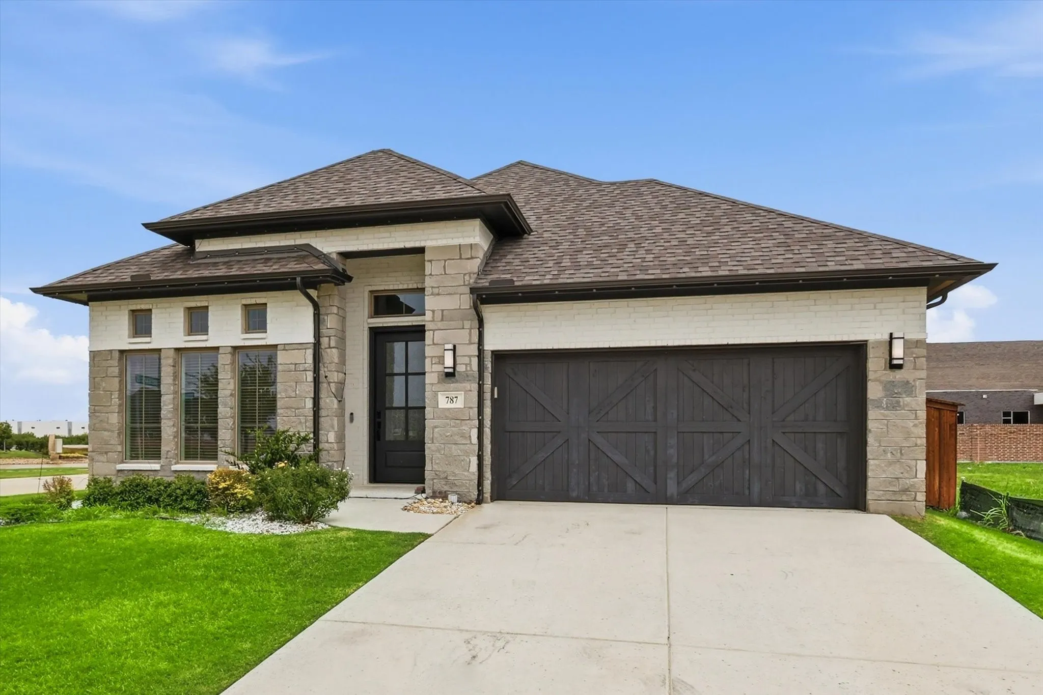 Contemporary single-story exterior featuring a blend of light-colored brick and stone masonry