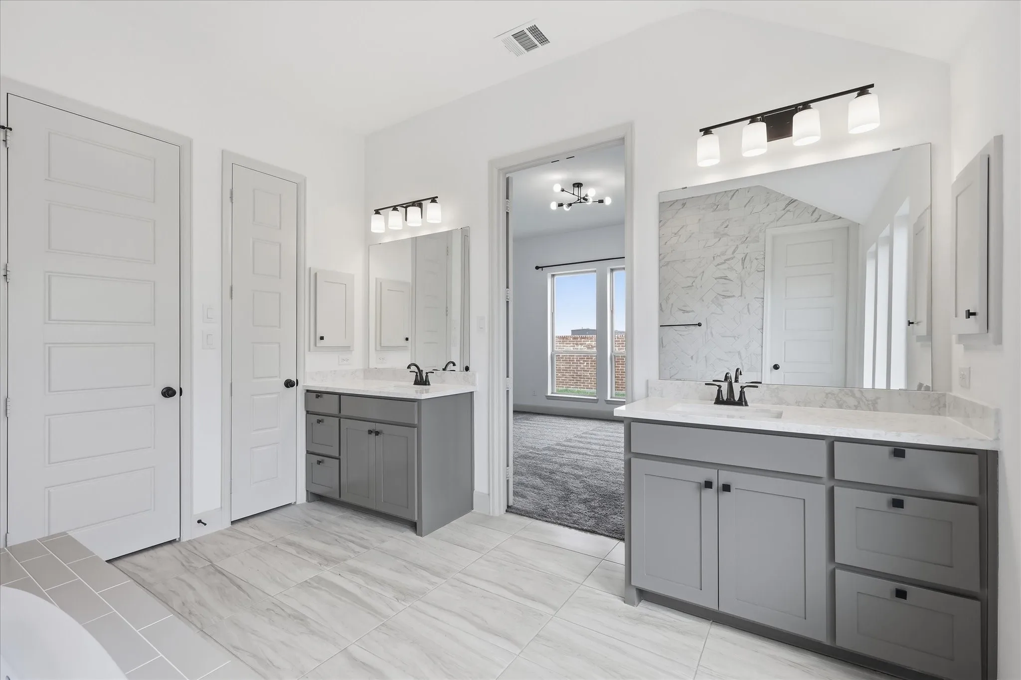 Dual vanity bathroom featuring gray cabinetry, light-toned countertops, and modern lighting fixtures