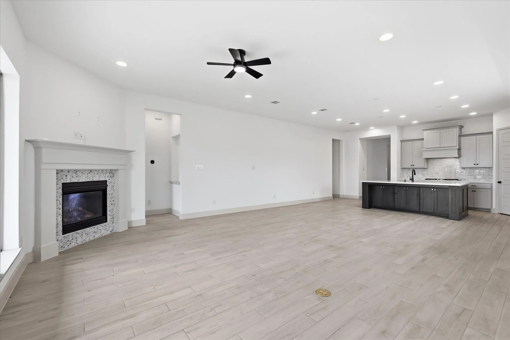 Expansive open-concept living area featuring light wood-finish flooring and recessed lighting