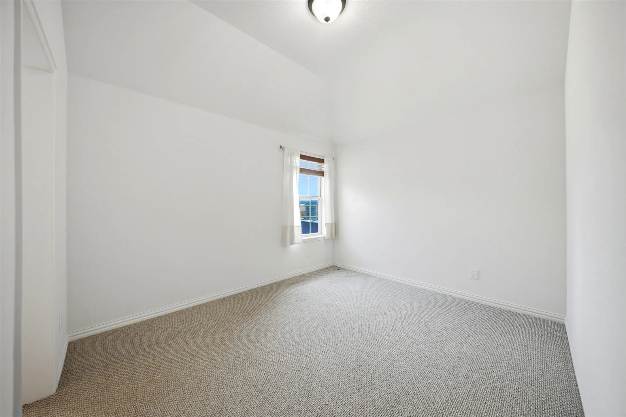Vaulted ceiling, neutral wall paint, single window, carpet flooring, flush mount light fixture