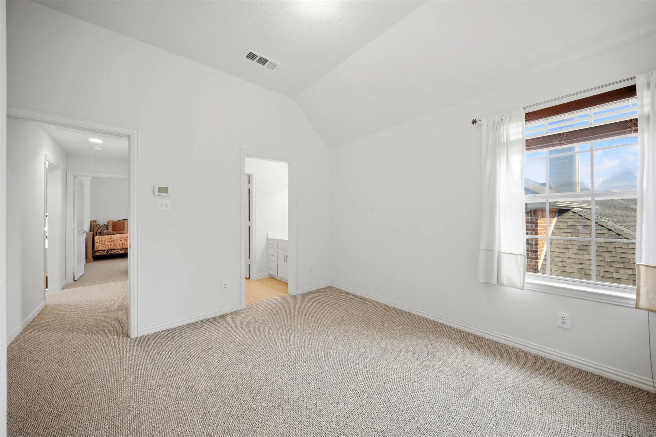 Vaulted ceiling, neutral carpet, white interior paint, and an operable window