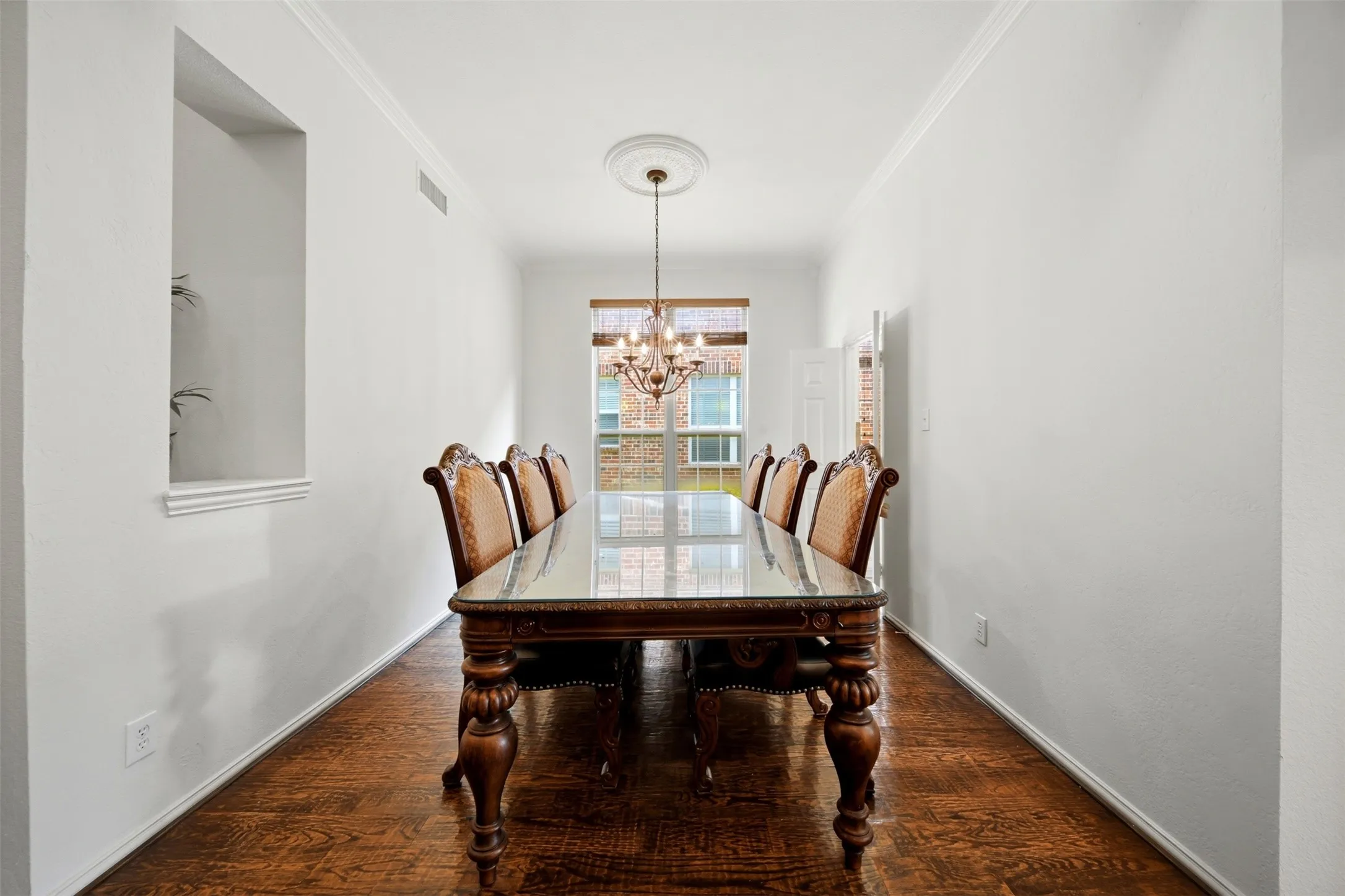 Recessed wall niche, crown molding, wood-finish flooring, and a window with blinds