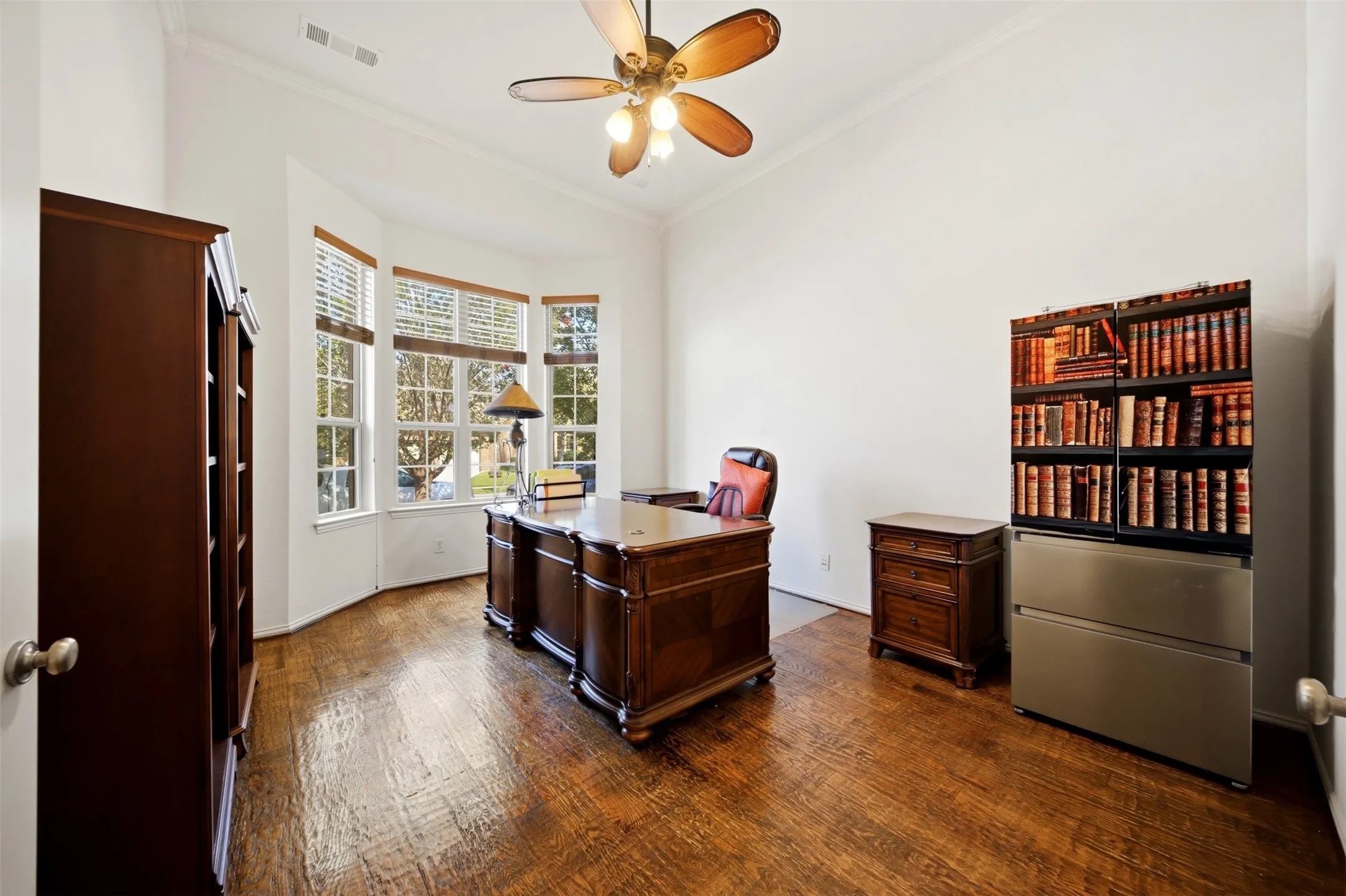 Hardwood flooring, bay windows with blinds, ceiling fan, and white walls