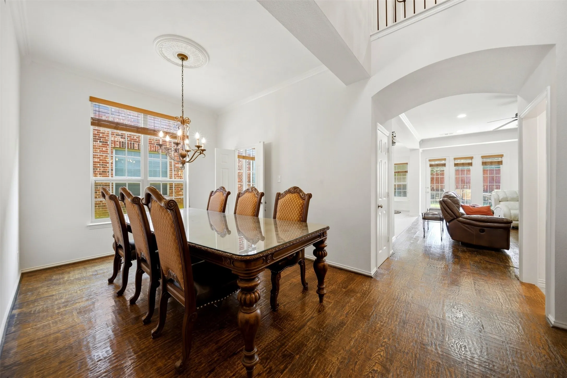 Hardwood flooring throughout, arched doorway, decorative ceiling medallion, built-in lighting, and a prominent window
