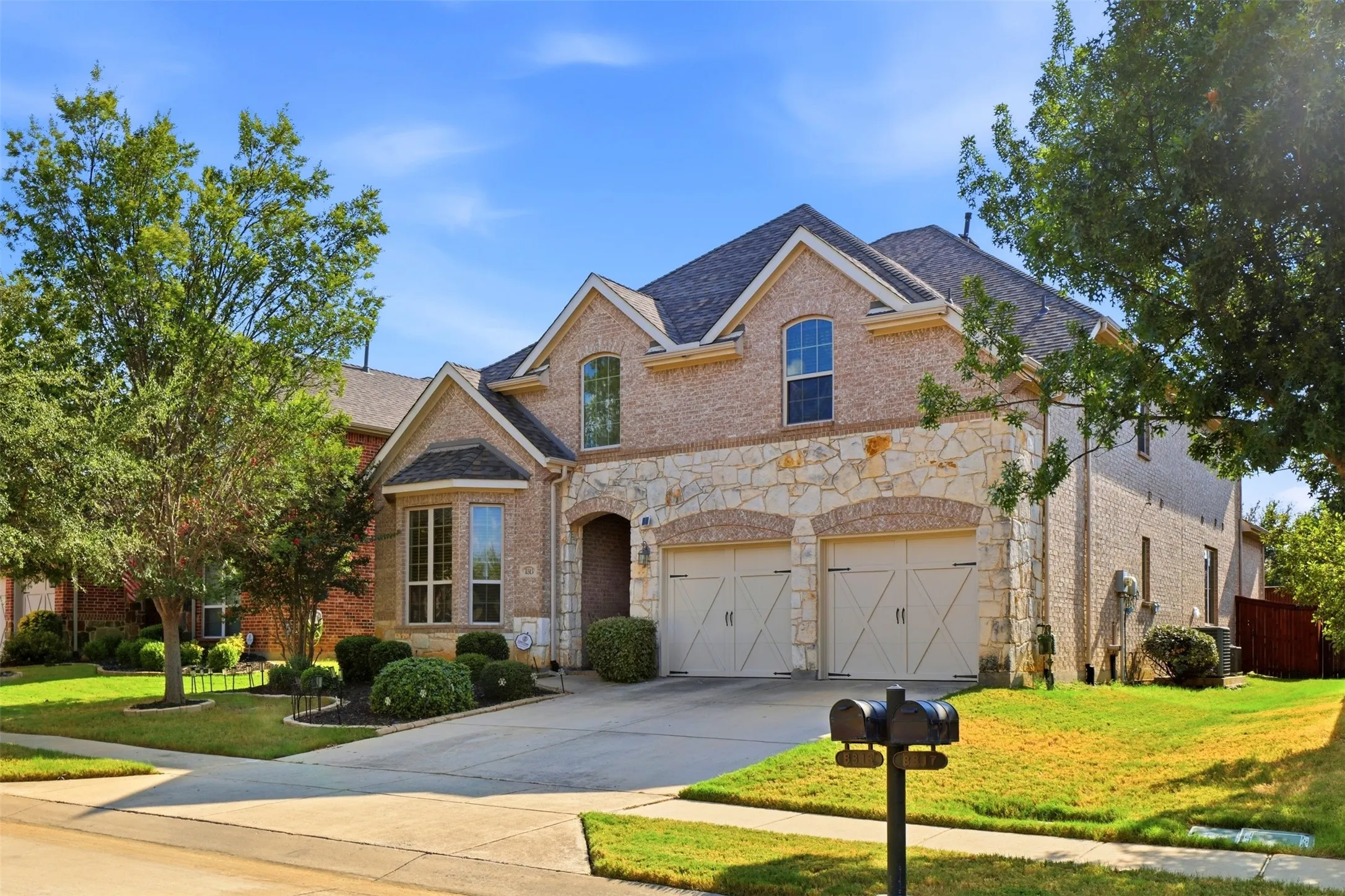 Brick and stone exterior featuring multiple gables, an arched entry, and a dual-door garage