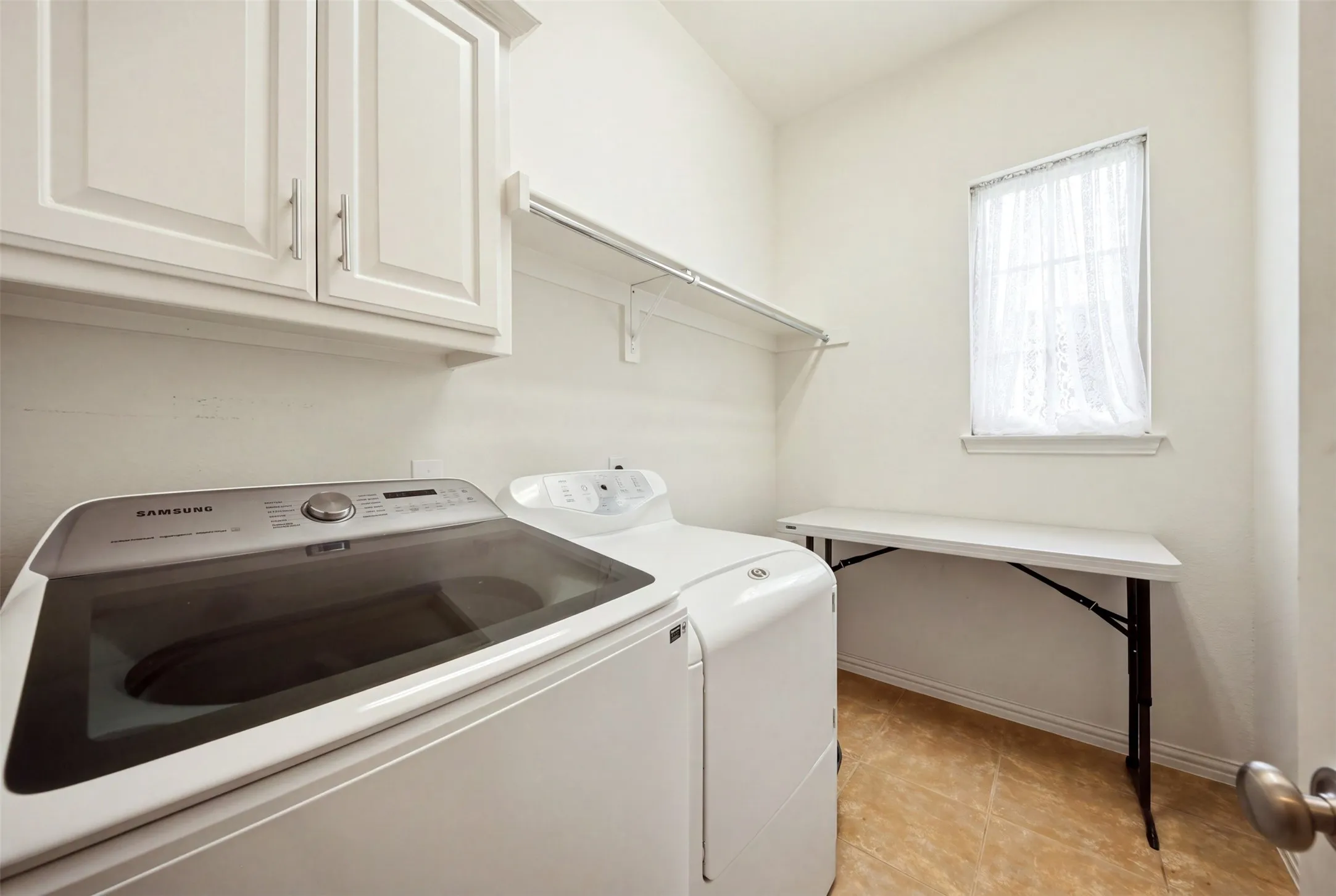Laundry area with upper cabinetry, open shelving, and tiled flooring