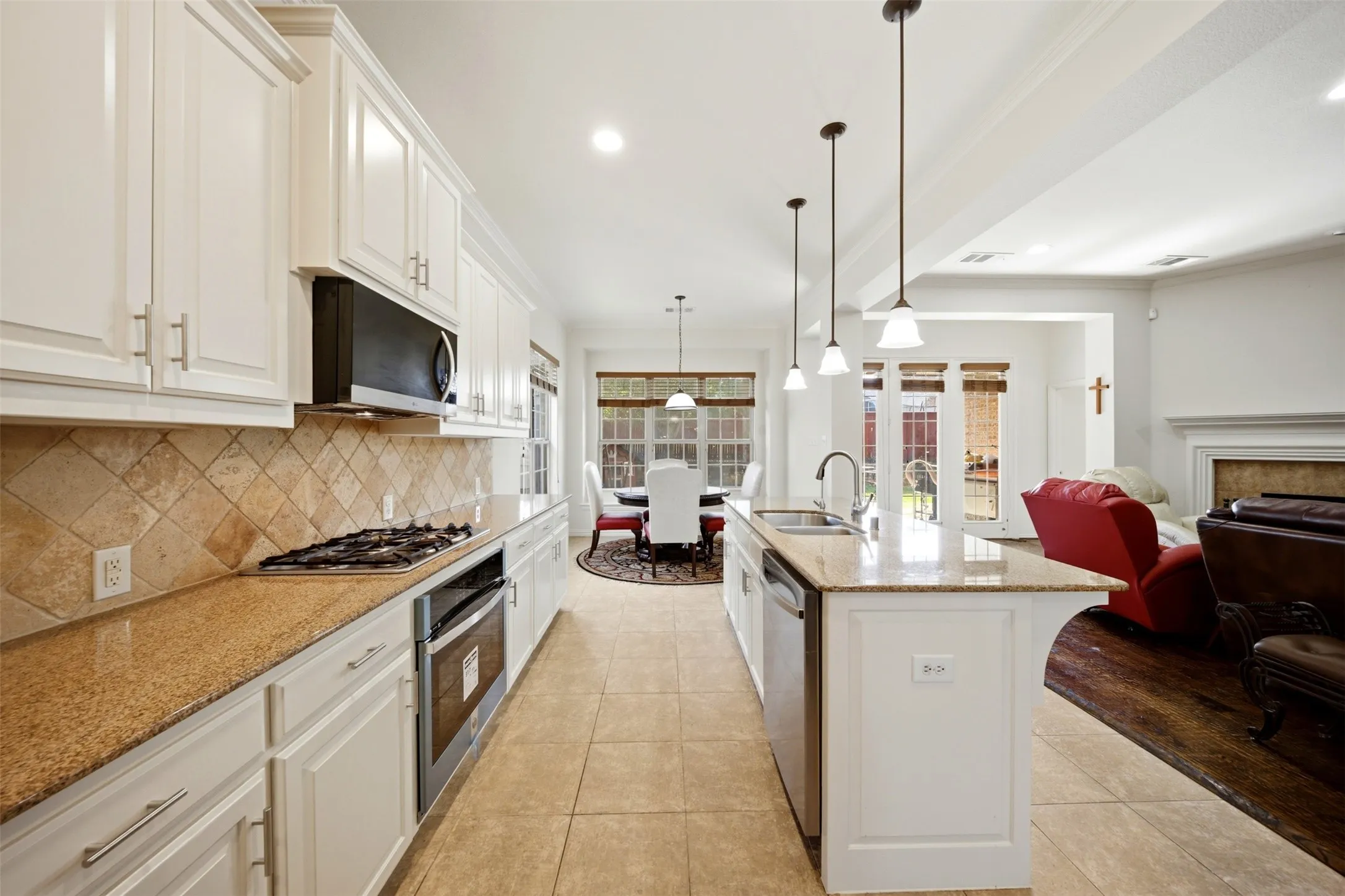 Kitchen features white cabinetry, stone countertops, a tile backsplash, and stainless steel appliances