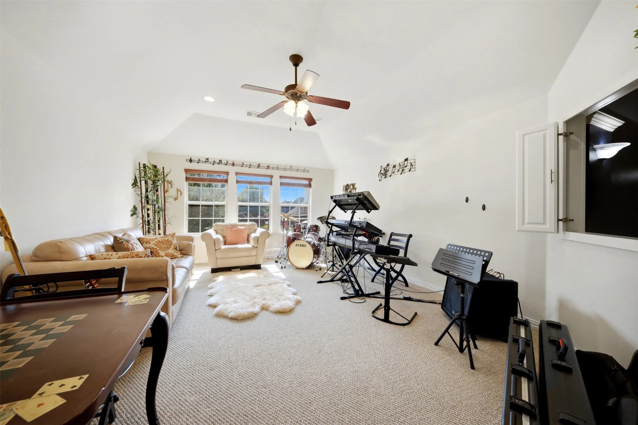 Vaulted ceiling with ceiling fan, carpeted flooring, window treatments, and built-in cabinetry