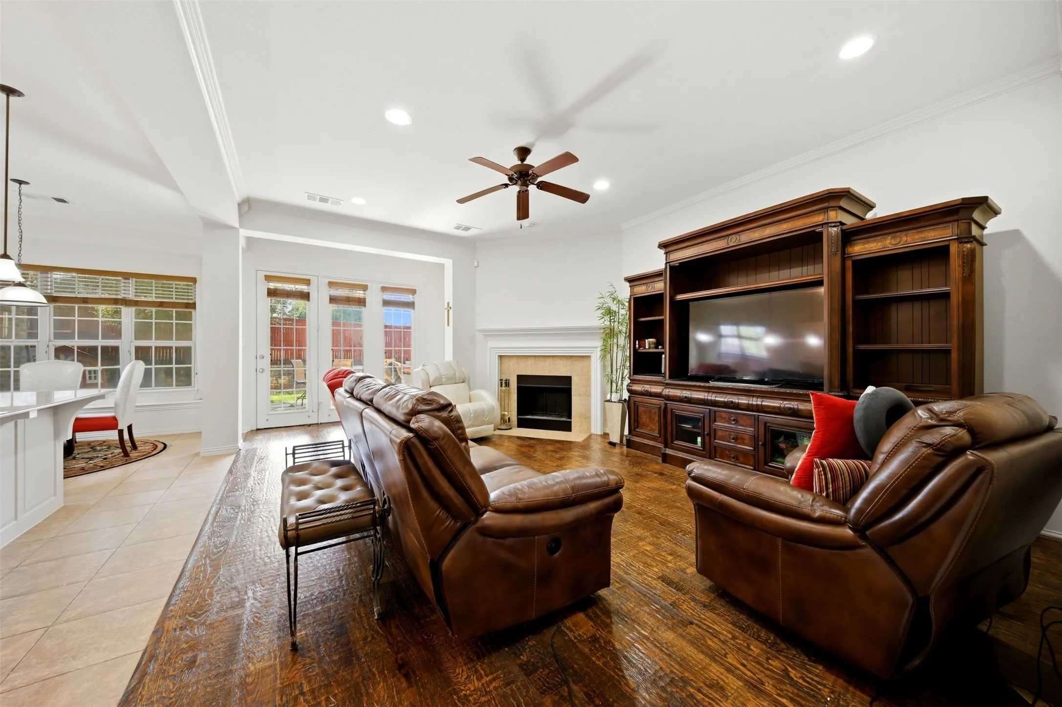 Spacious living area featuring wood-finish flooring, a ceiling fan, a built-in entertainment center, a fireplace with a mantel, and recessed lighting