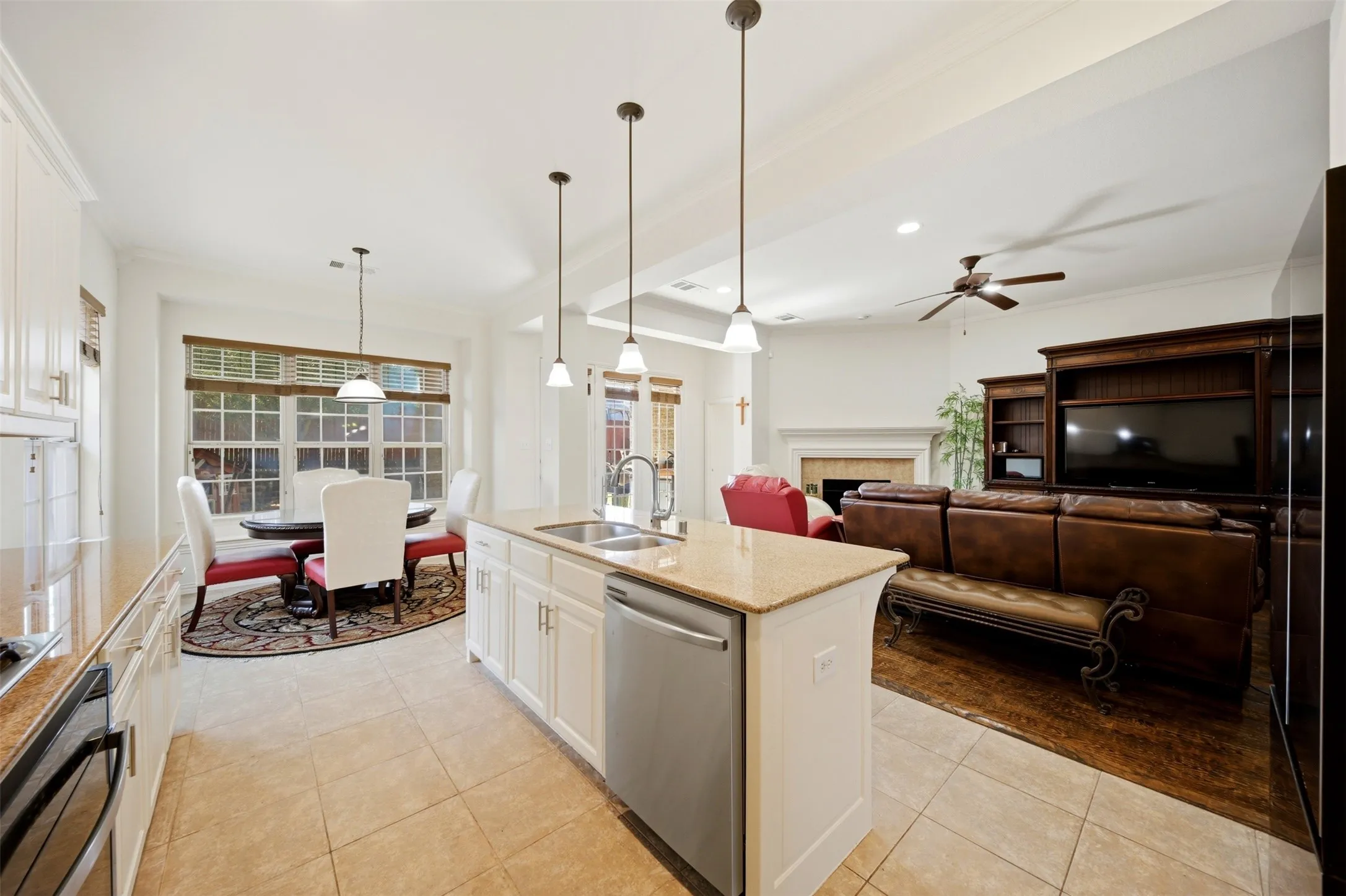 Kitchen island with integrated sink, stainless steel dishwasher, and pendant lighting