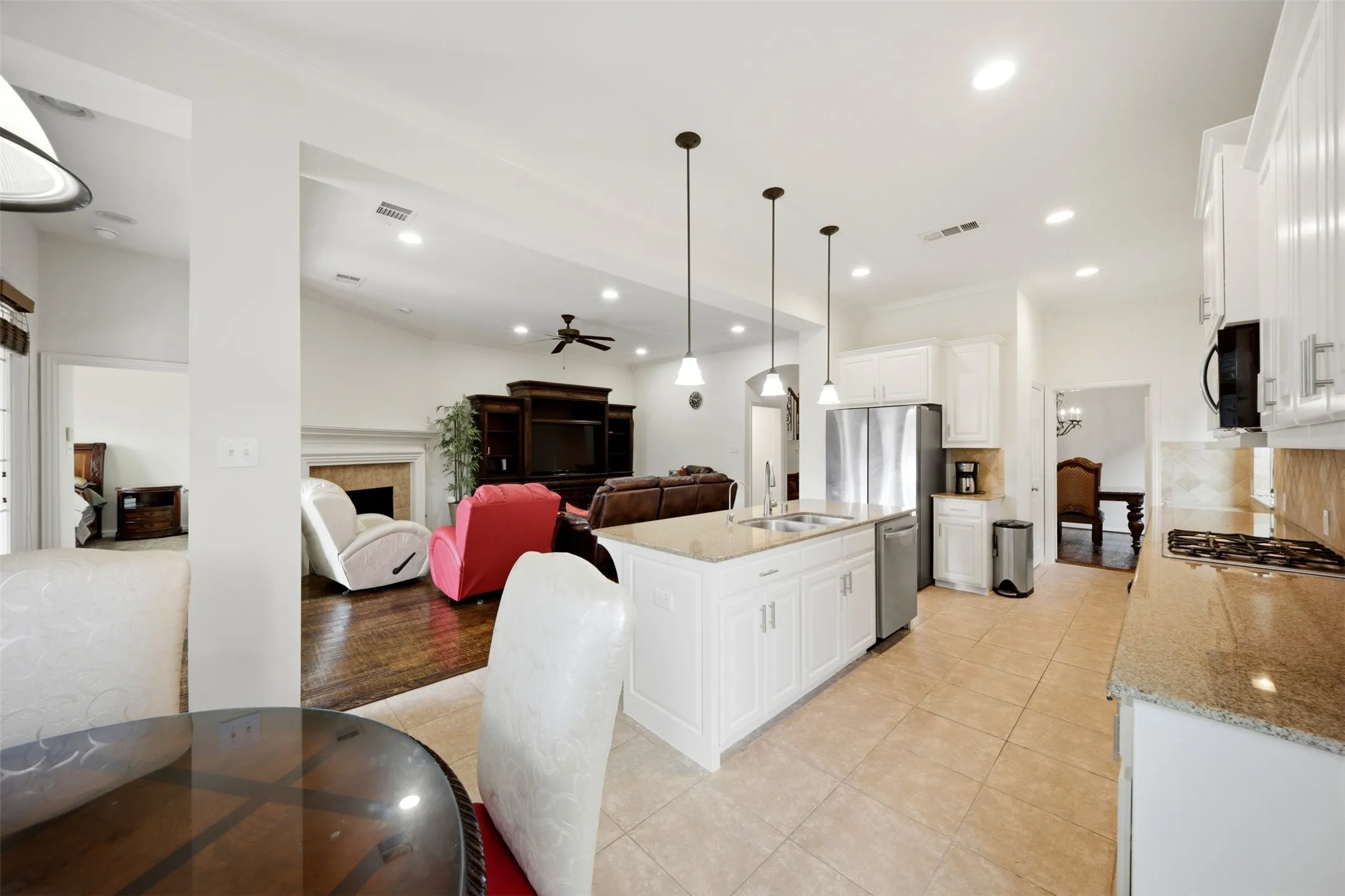 Kitchen featuring tile flooring, white cabinetry, a center island with a sink, stainless steel appliances, and pendant lighting