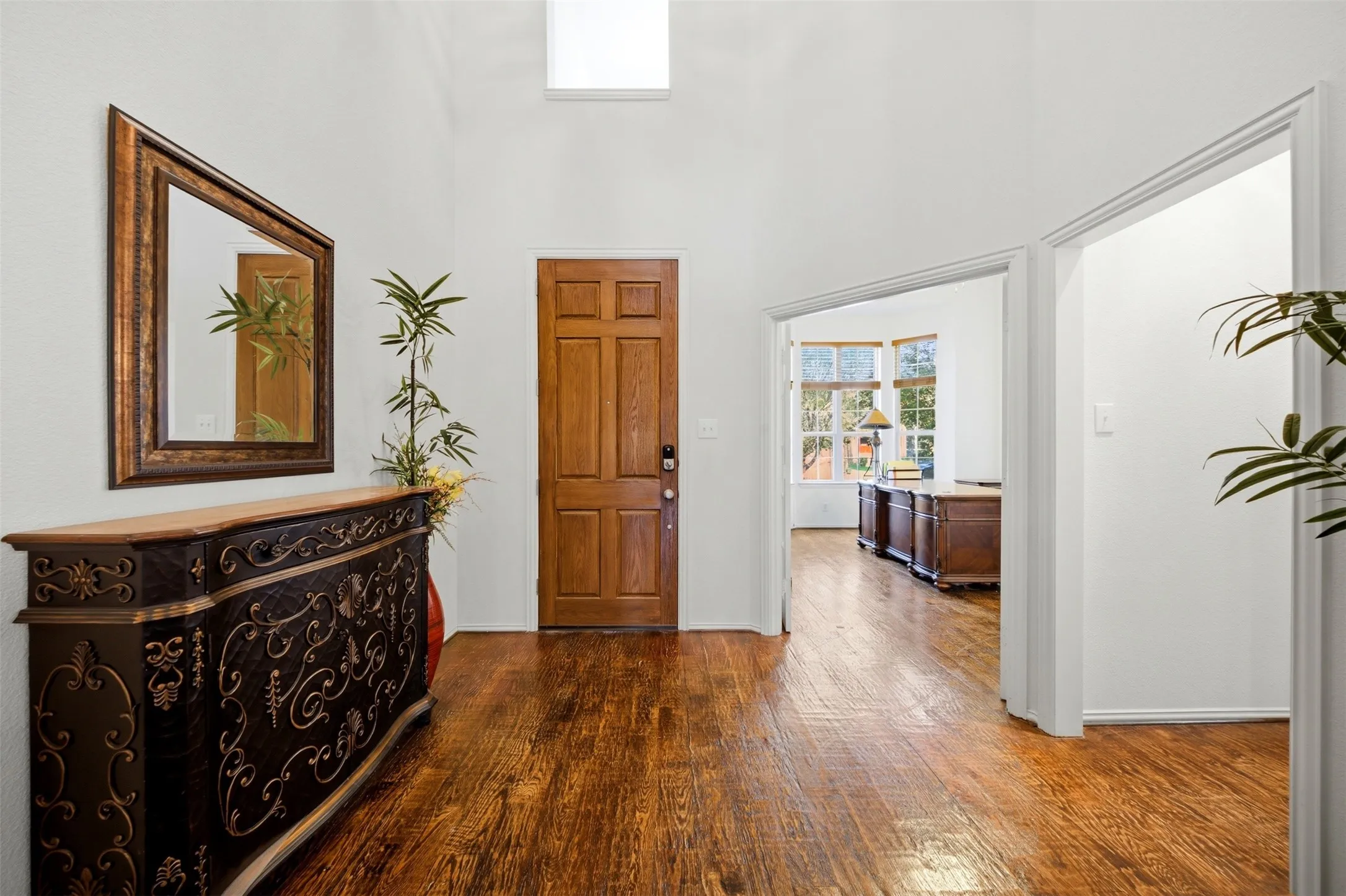 Wood-finish flooring throughout, light wood door, transom window, and white walls