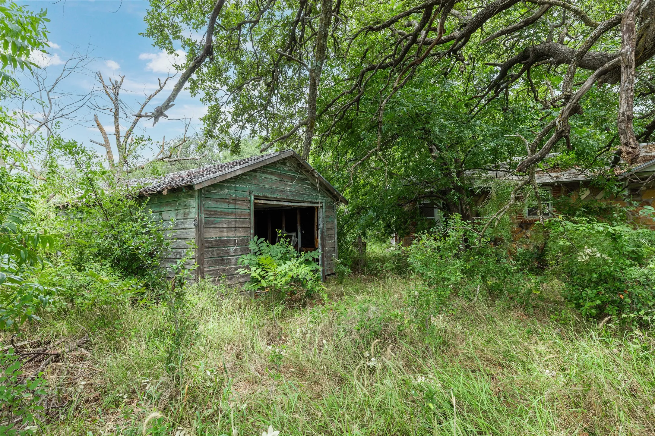 Detached structure with weathered wood siding and an open bay