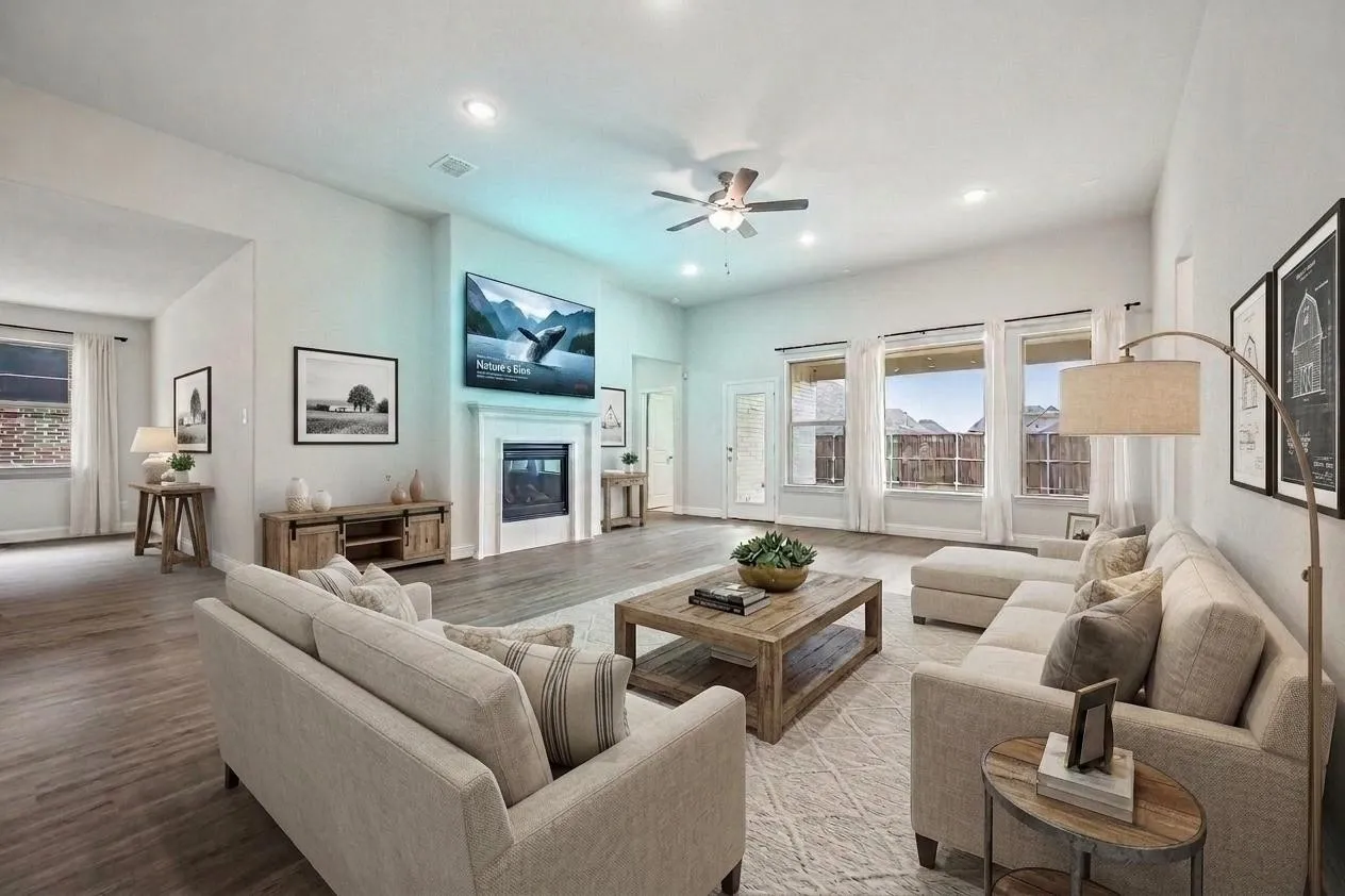 Spacious living area featuring high ceilings, wood-finish flooring, and a fireplace with a white mantel