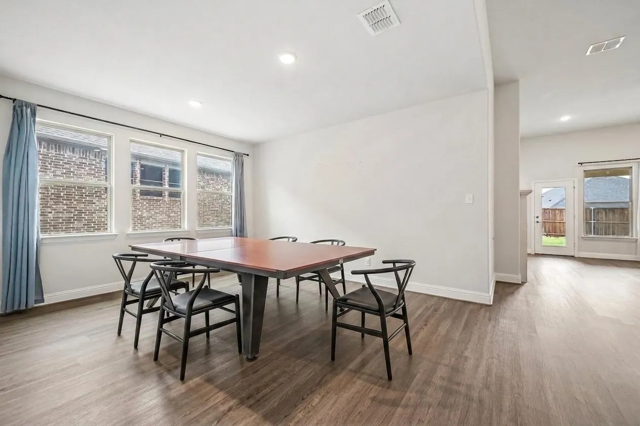 Spacious room featuring wood-finish flooring, recessed lighting, and multiple windows with white trim