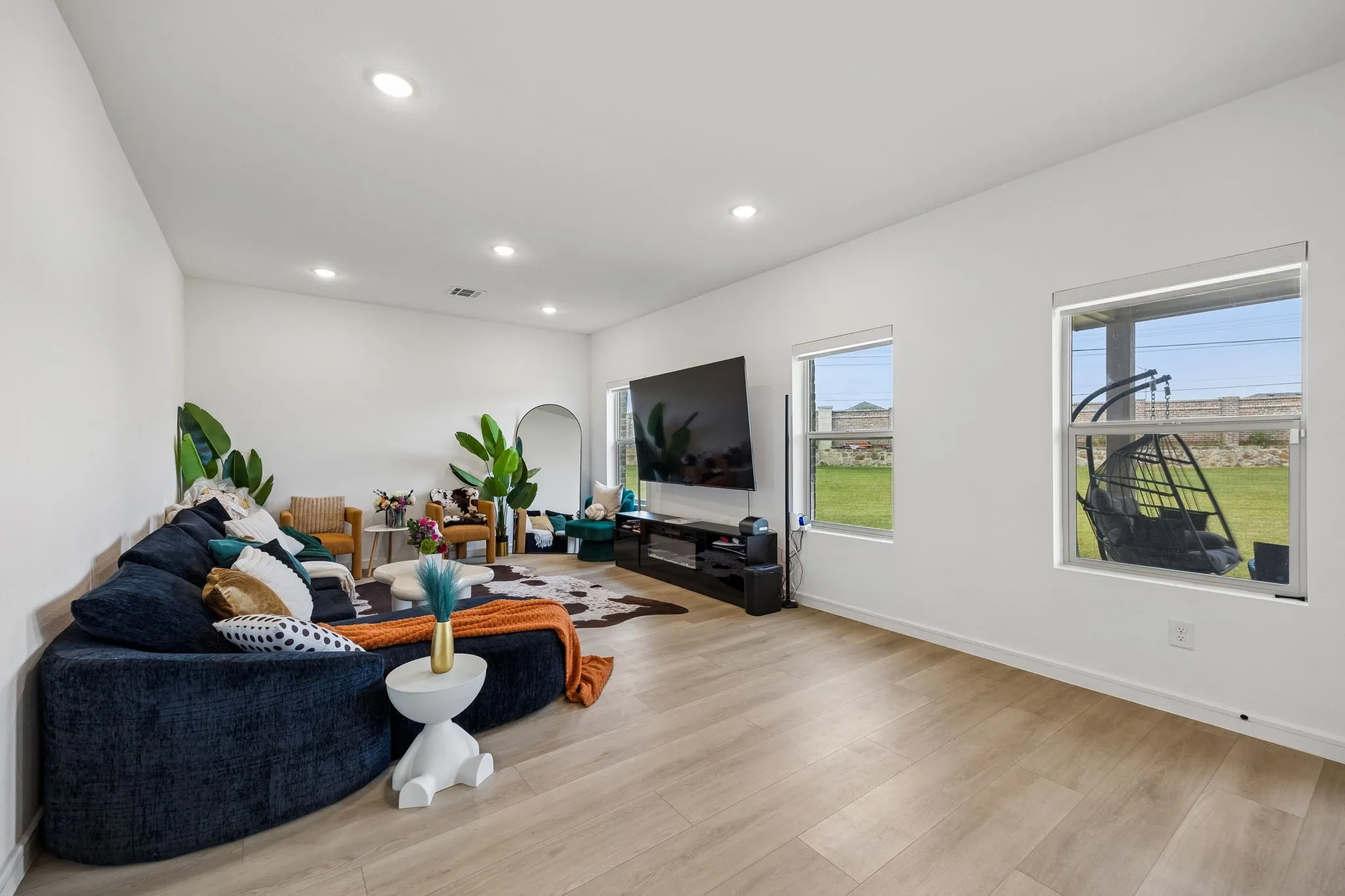 Spacious living area featuring light wood-finish flooring, white walls, and recessed lighting