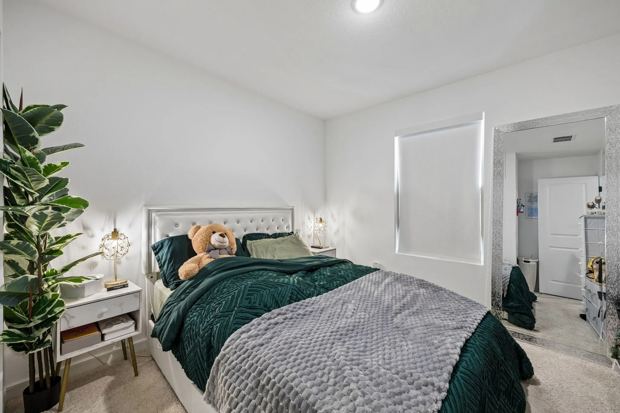 Bedroom featuring a tufted upholstered headboard, recessed ceiling lighting, a window with roller shade, and light-colored carpeting