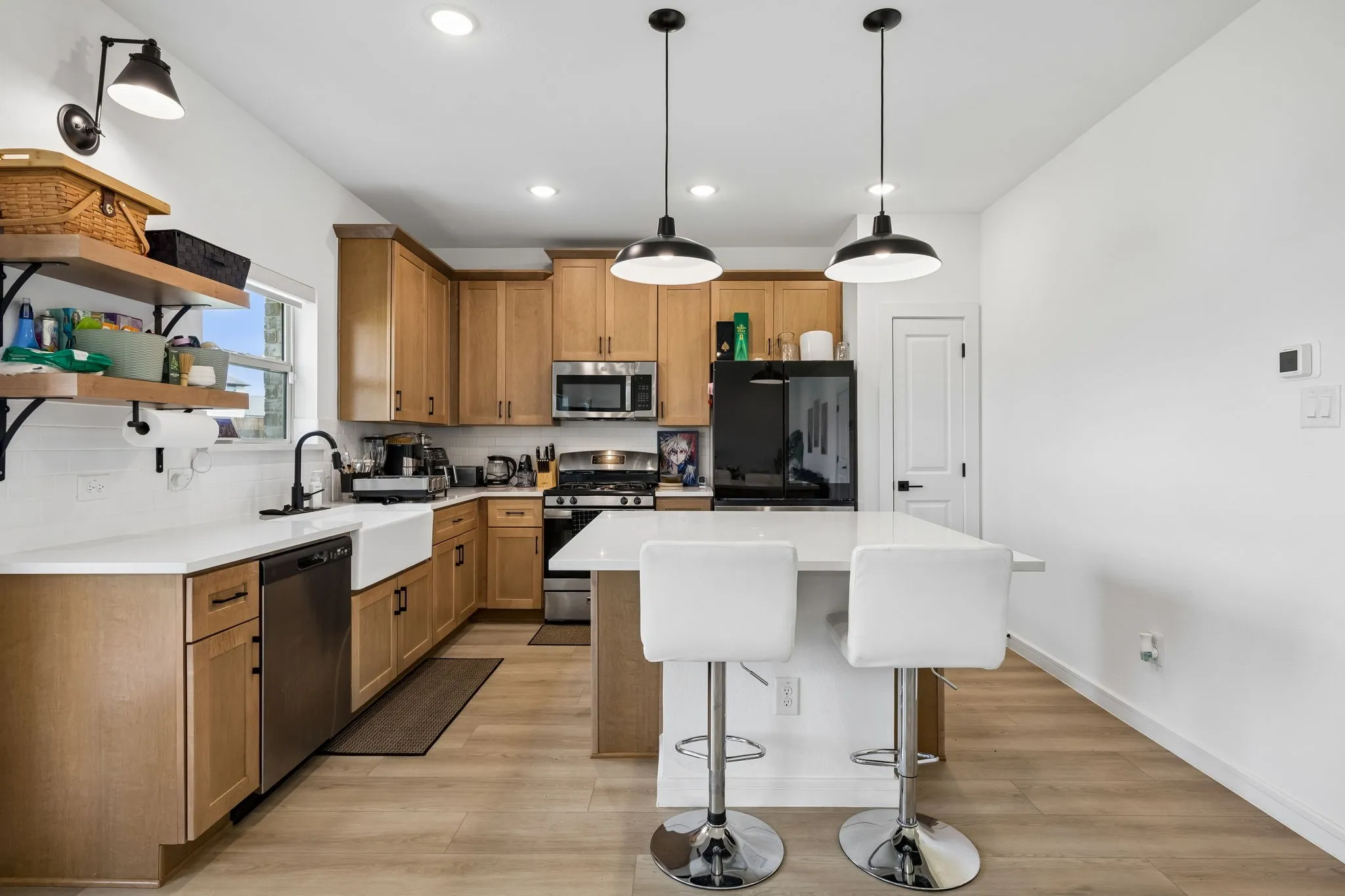 Kitchen featuring wood-finish cabinetry, white countertops, stainless steel appliances, and a central island with pendant lighting