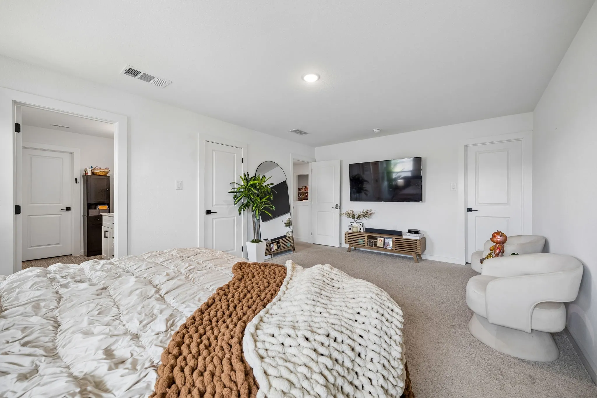 Bedroom featuring light gray carpeting, crisp white walls, recessed ceiling lighting, and multiple white doors with matte black hardware