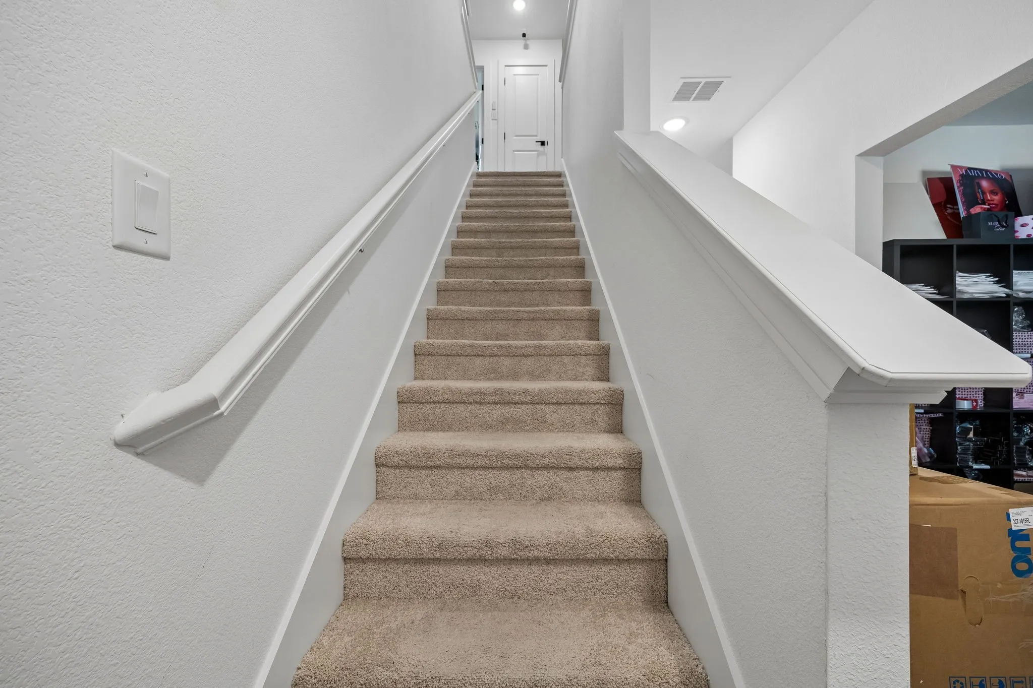 Carpeted staircase with white painted handrail and trim