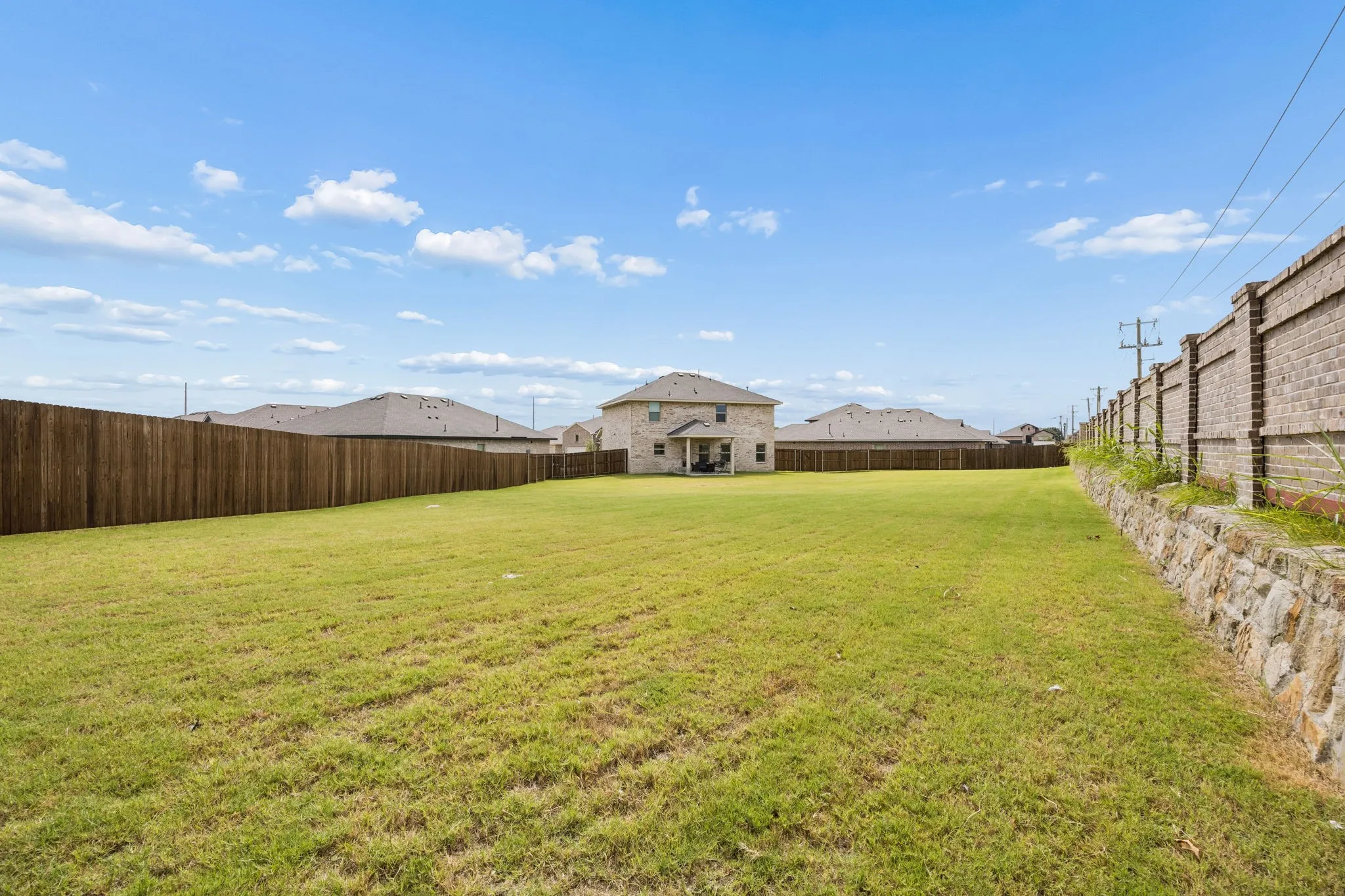 Expansive grassy yard with a wooden privacy fence