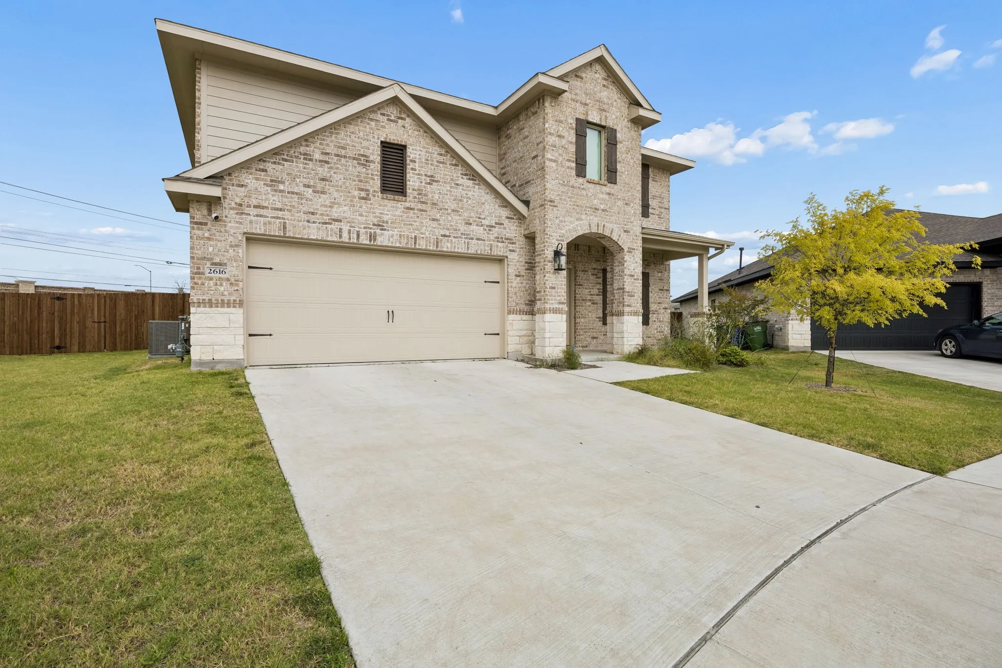 Two-story residence featuring a brick and stone facade, an arched entryway, an attached two-car garage, and a concrete driveway