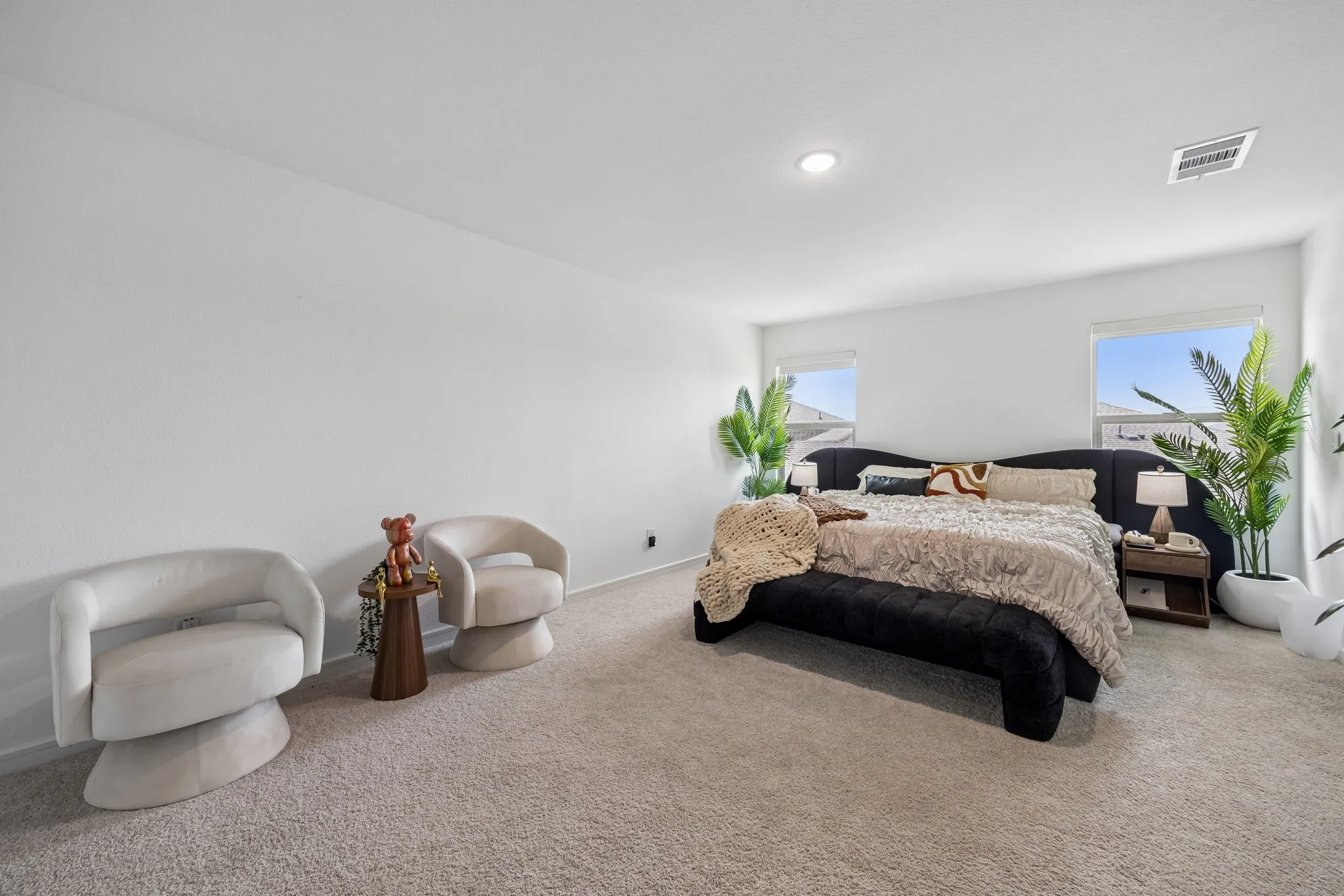 Spacious room featuring neutral carpeting, recessed lighting, and two windows providing natural light