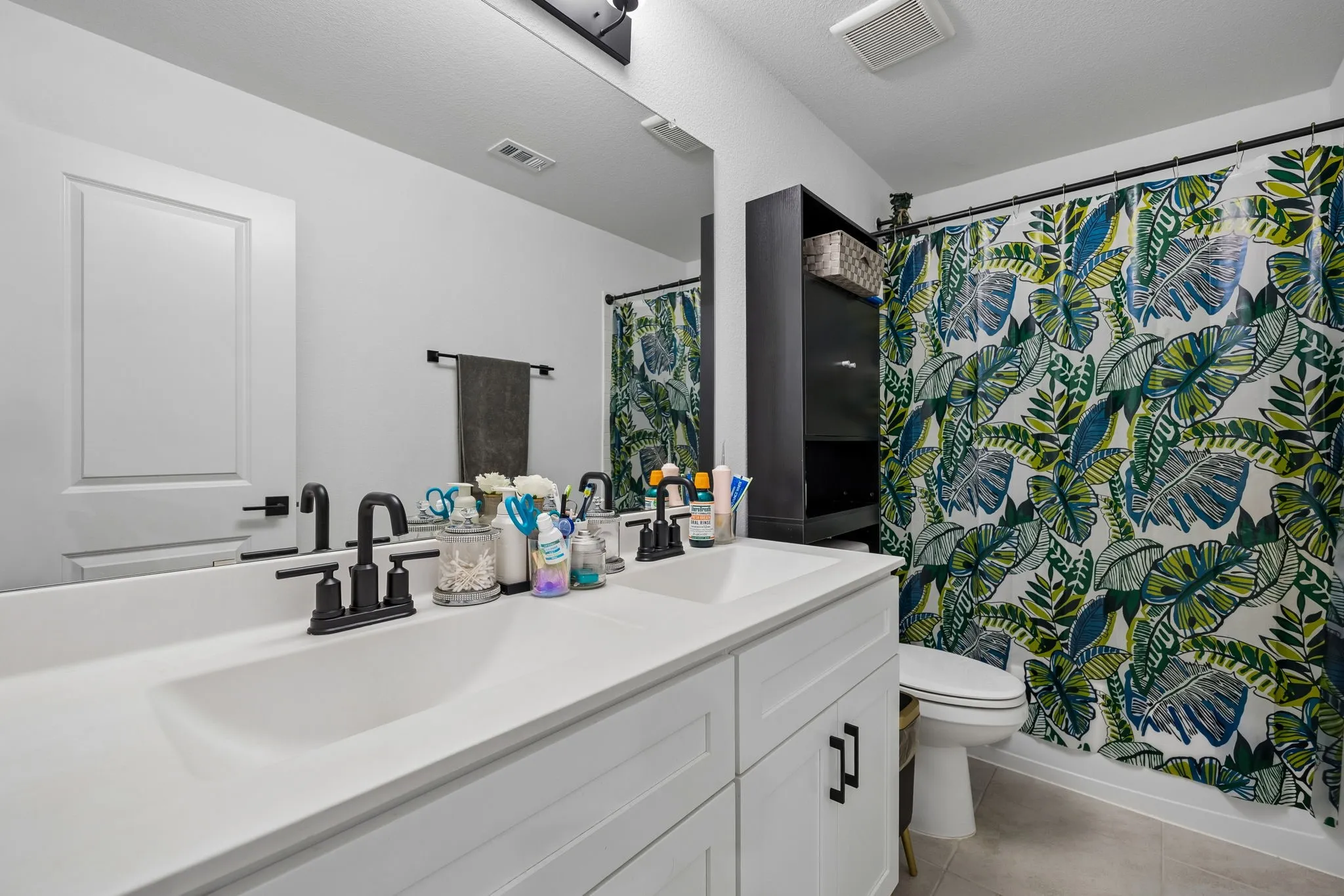 Dual vanity with integrated sinks and matte black fixtures, white shaker cabinetry, and a full-width mirror
