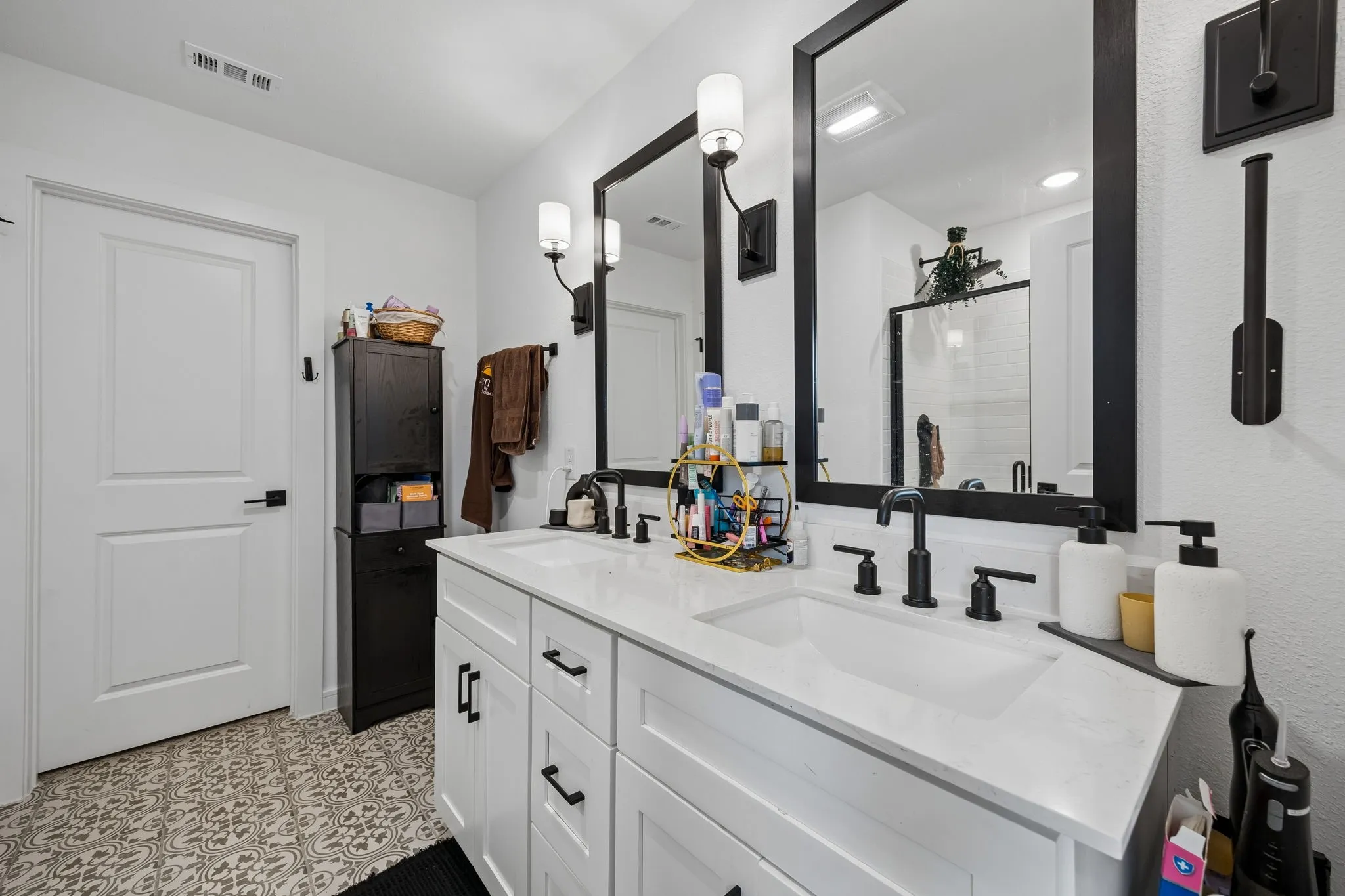 Dual vanity featuring white shaker cabinetry, matte black hardware, and an integrated countertop with two undermount sinks