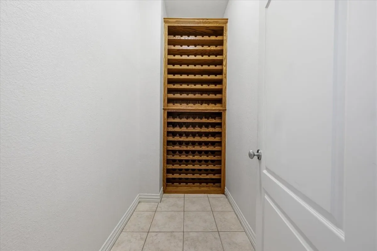 Built-in wood wine racks with ample storage capacity, framed by light-toned walls and tiled flooring