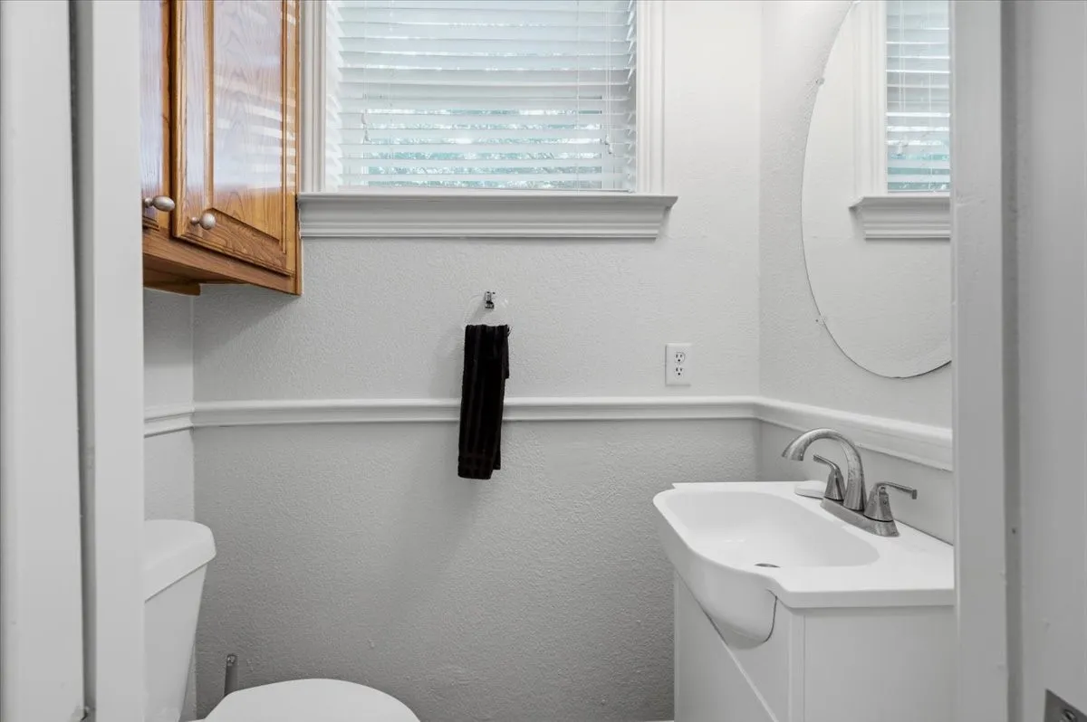 Bathroom featuring a white pedestal sink, chrome fixtures, and an oval wall mirror