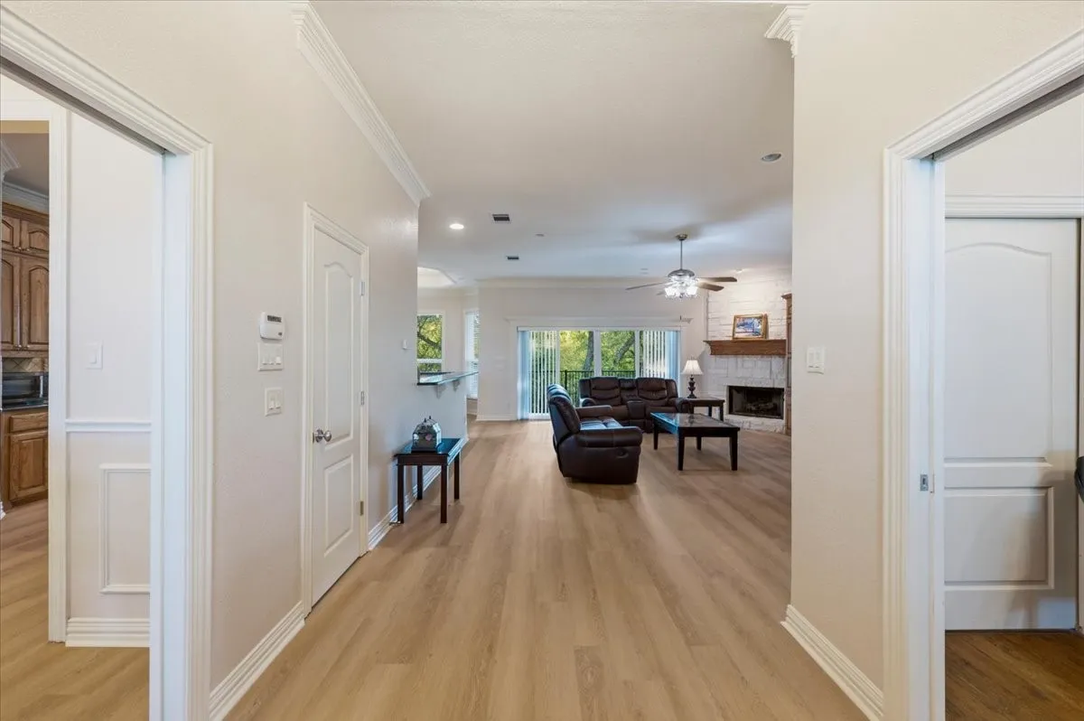 Open-concept living space with wood-finish flooring throughout, a vaulted ceiling, and crown molding