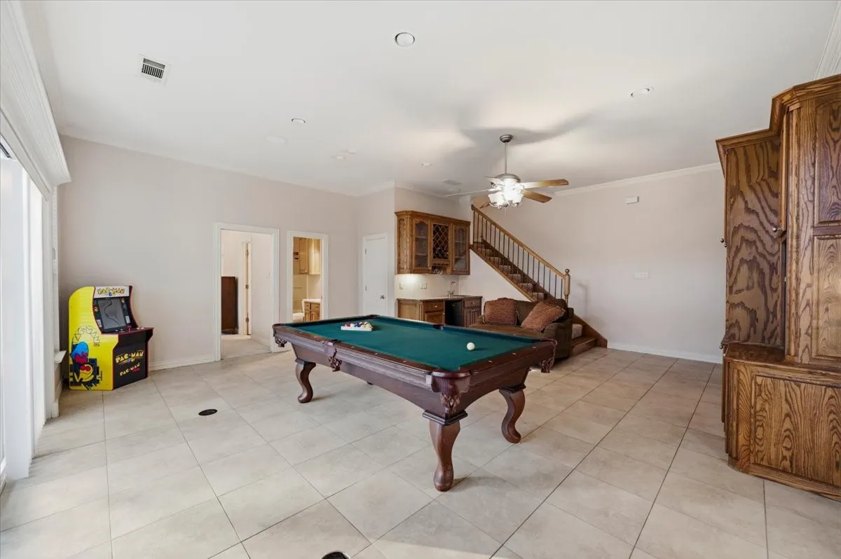 Spacious recreation room featuring light-toned tile flooring, recessed lighting, and a neutral wall color