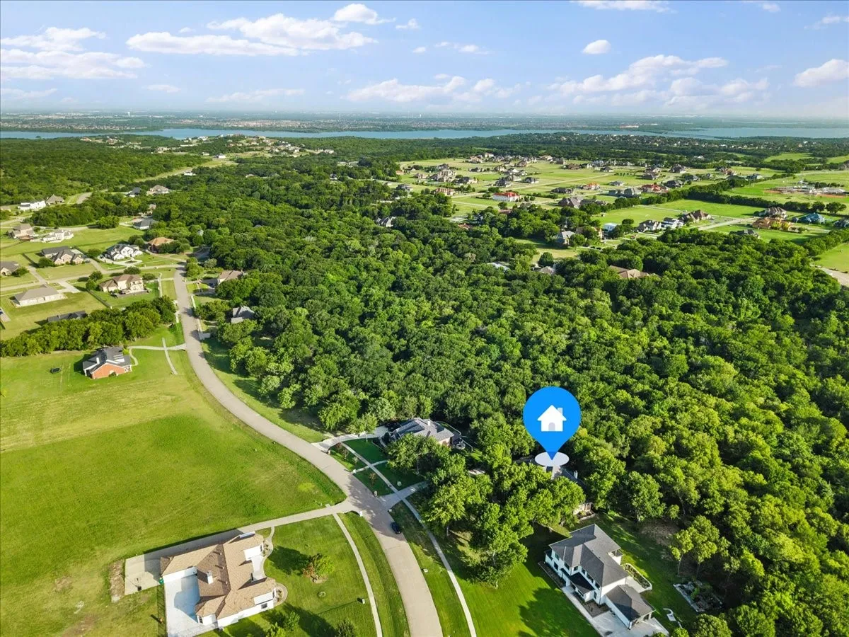Aerial view showcasing a residential property surrounded by mature trees