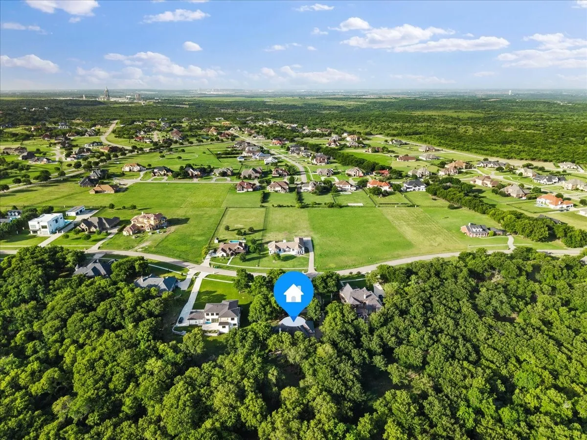 Expansive aerial highlighting a residential property set amidst mature trees