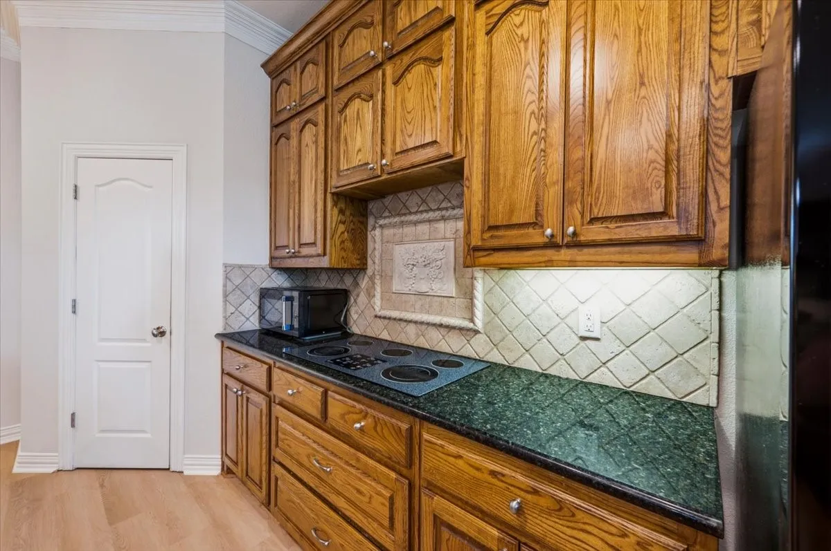 Kitchen featuring wood cabinetry, a built-in cooktop, and green speckled countertops