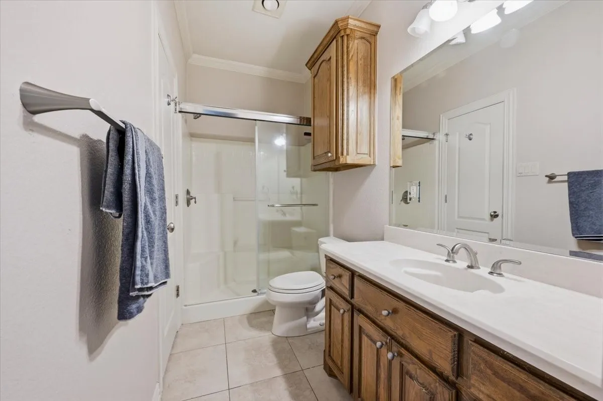 Bathroom featuring a wood-finish vanity with an integrated white sink, chrome fixtures, and a large mirror