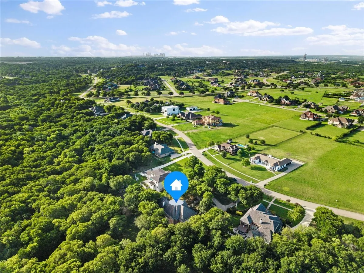 Aerial perspective showcasing a residential neighborhood with a mix of wooded and open green spaces