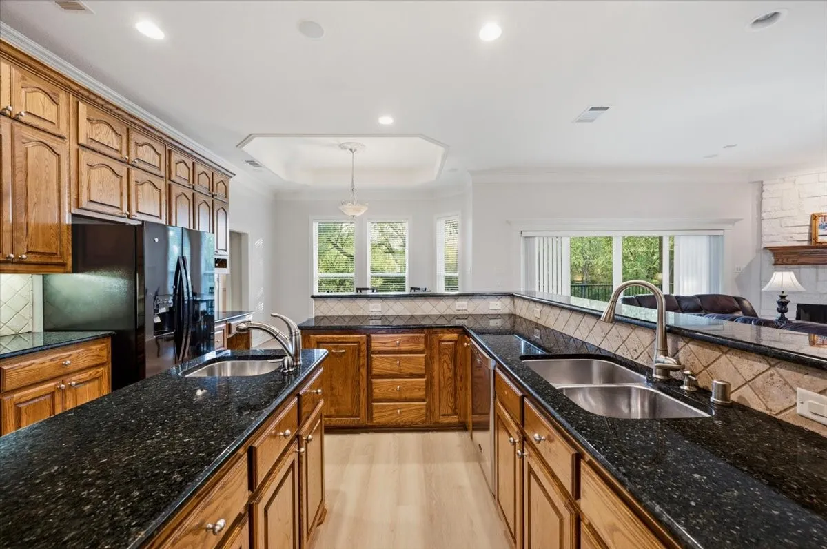 Kitchen featuring abundant wood cabinetry, dark speckled countertops, and stainless steel double sinks