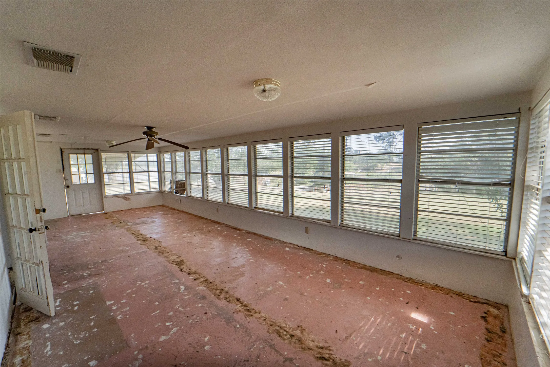 Sunroom featuring waterfront views,  multiple windows with blinds, a ceiling fan, and access to the exterior through a glass-paneled door