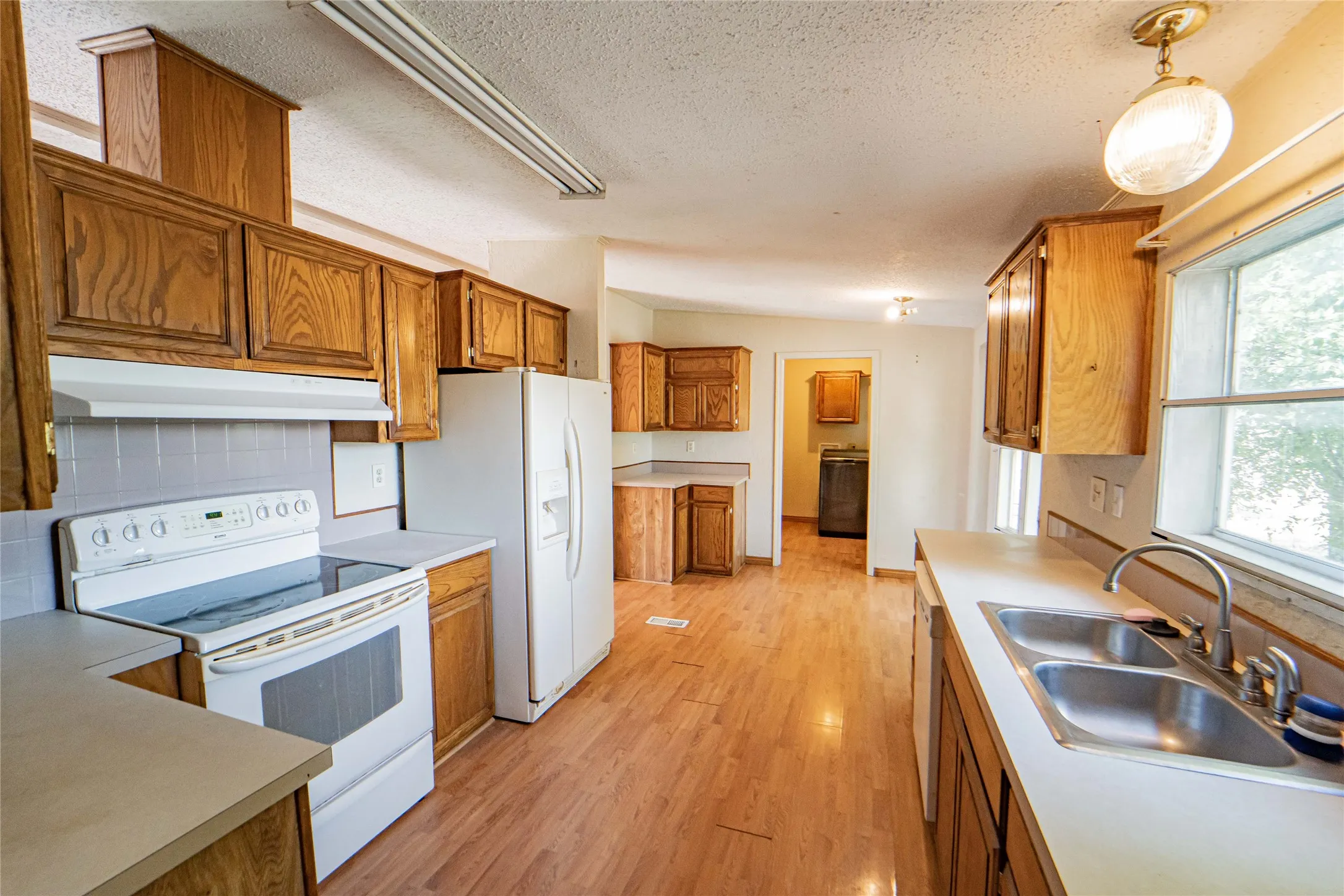 Kitchen with wood-finish flooring, wood cabinetry, laminate countertops, and a double basin stainless steel sink