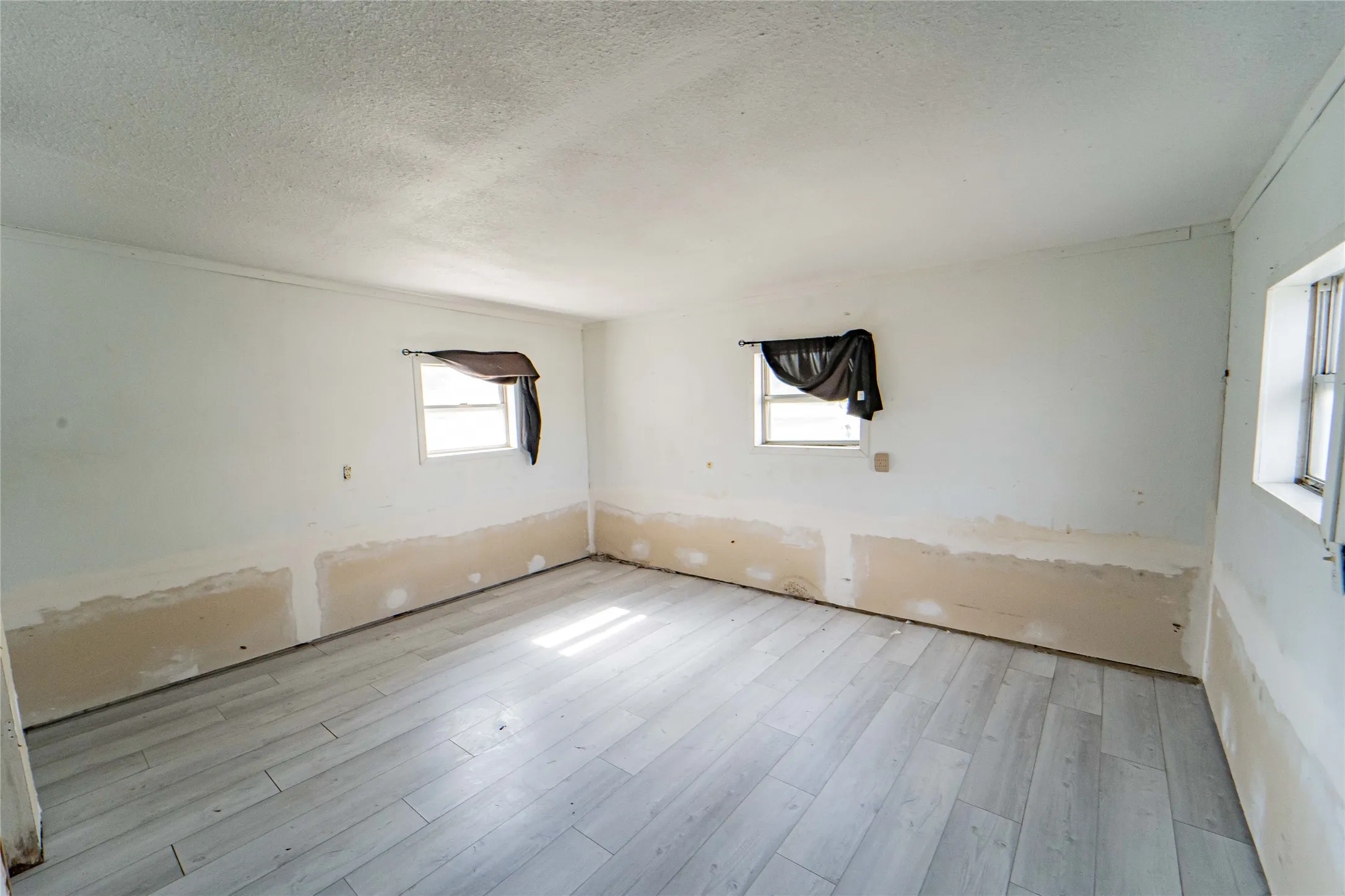 Guest Quarters offers large Bedroom- featuring wood-finish flooring, multiple windows, and a textured ceiling