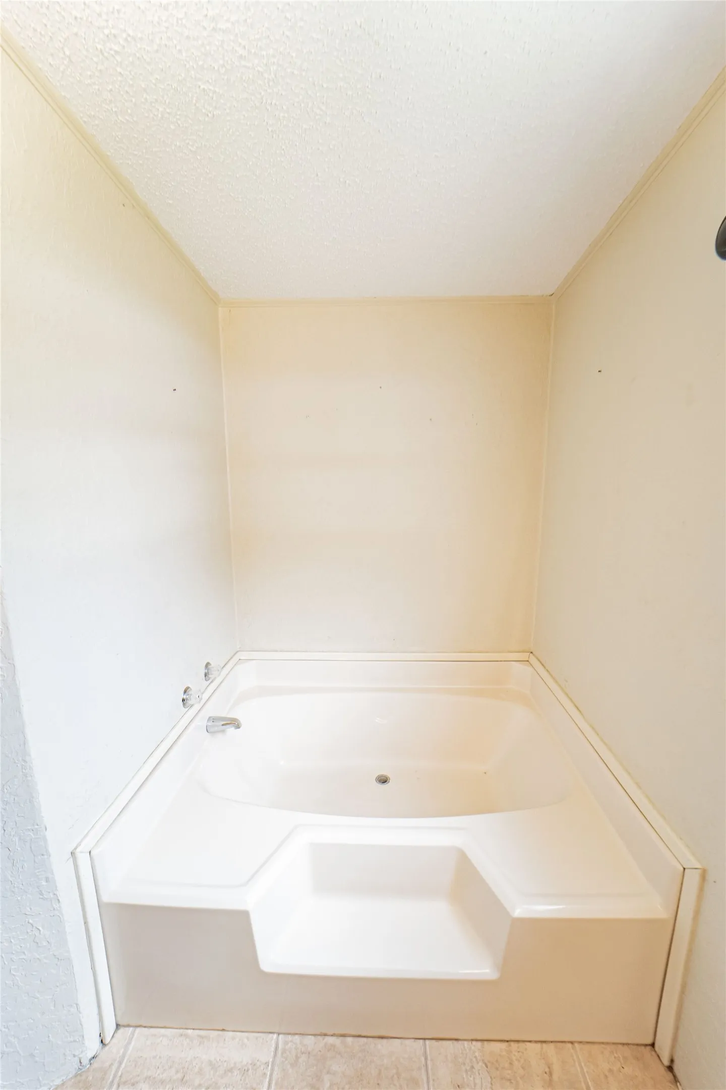 Built-in corner bathtub with integrated steps and a chrome faucet