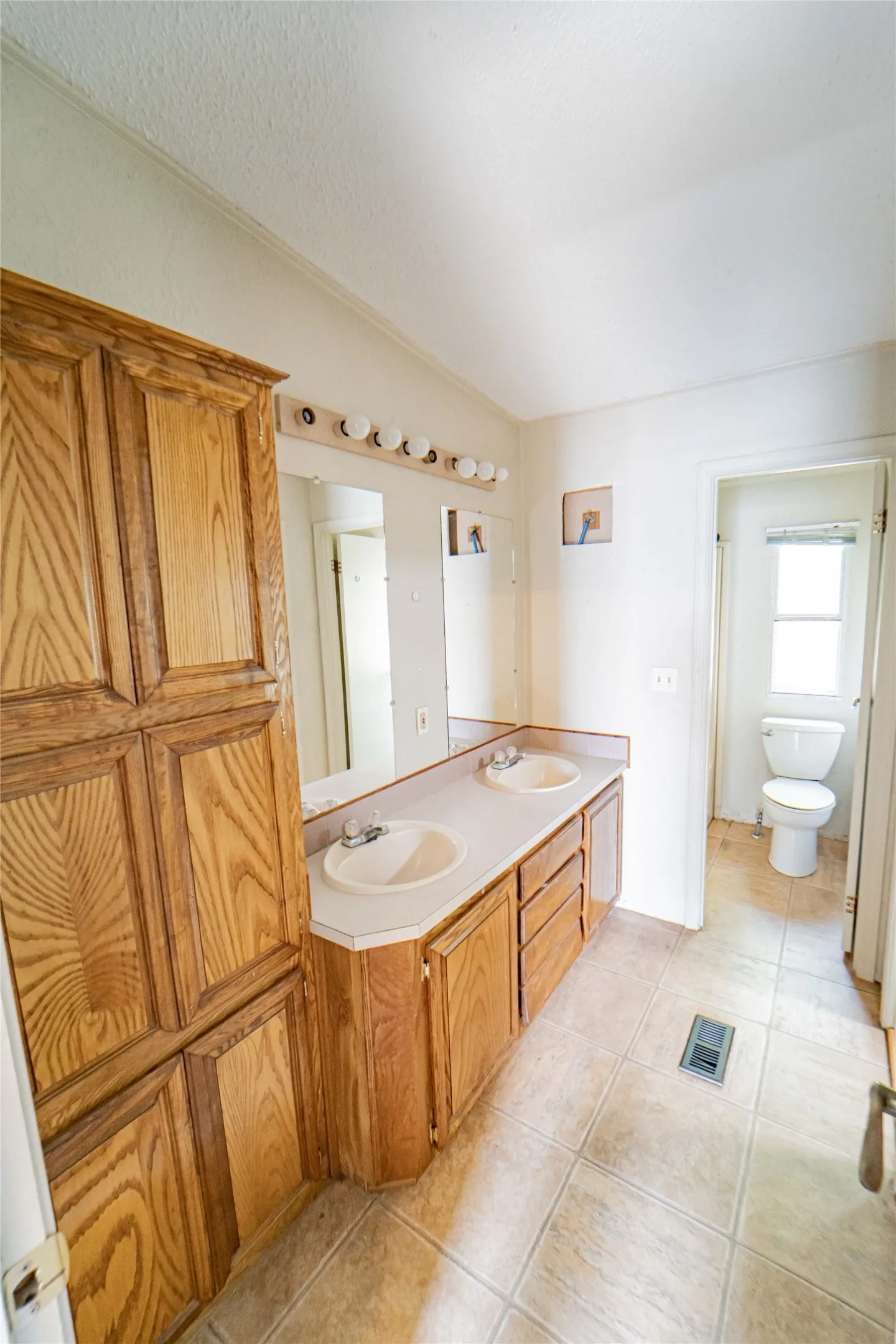Bathroom featuring a double vanity with integrated sinks and a large wood-finish storage cabinet