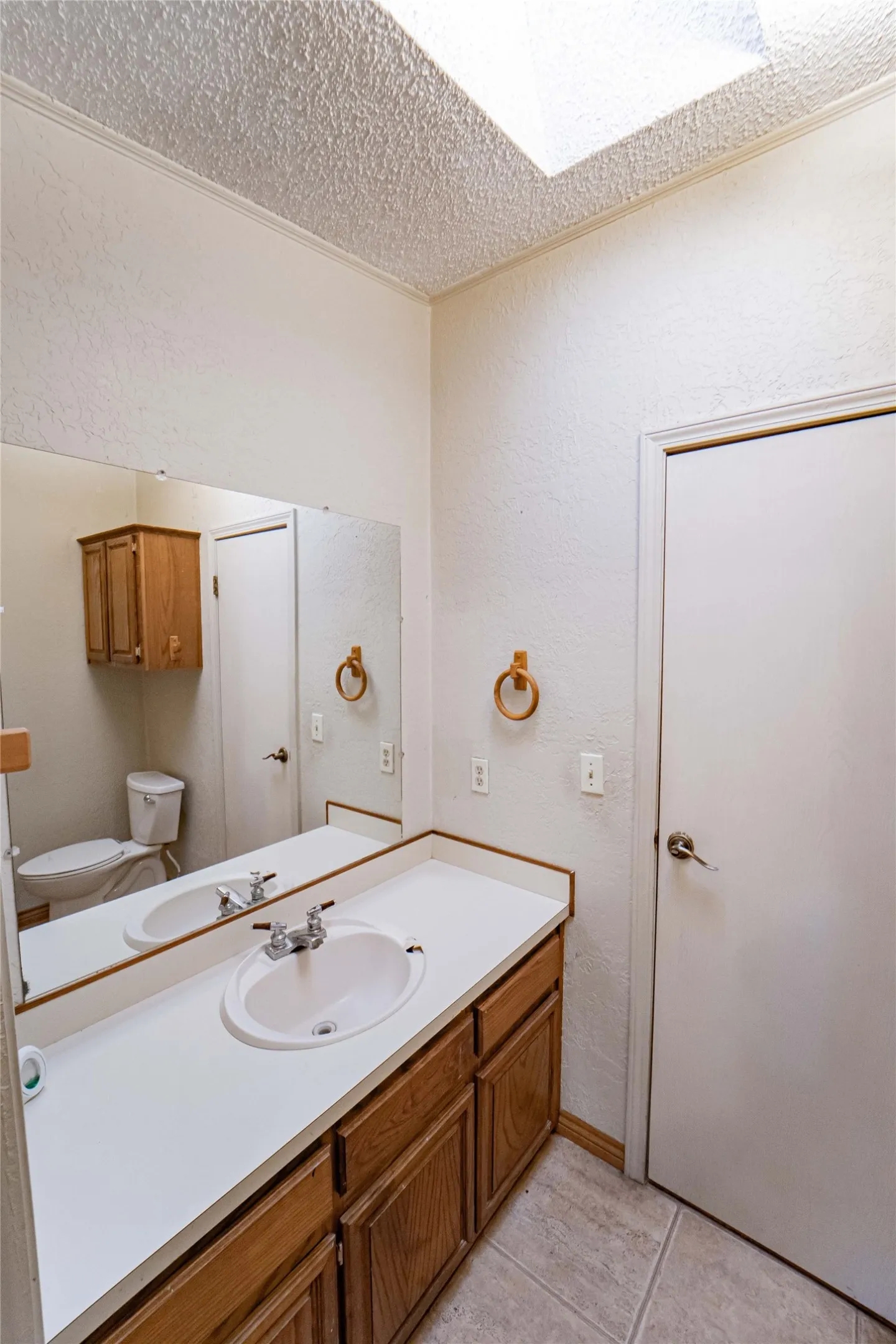 Bathroom featuring a vanity with a white countertop, an integrated sink, and wood-finish cabinetry
