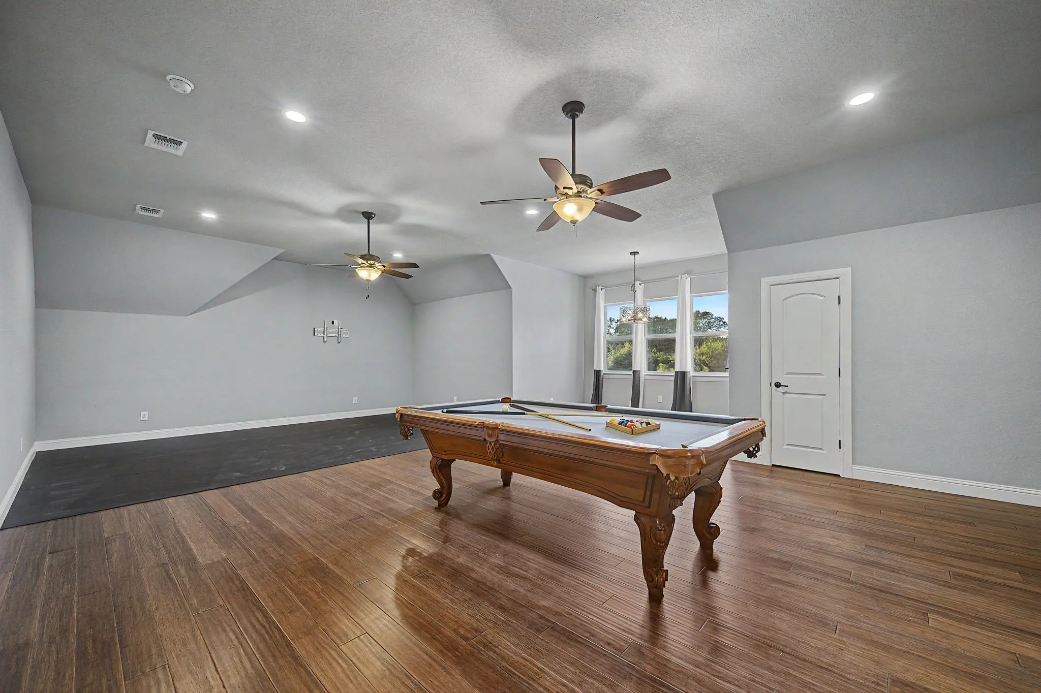 Spacious upstairs game room offers flexible use with an additional padded flooring area suitable for a home gym or fitness space.