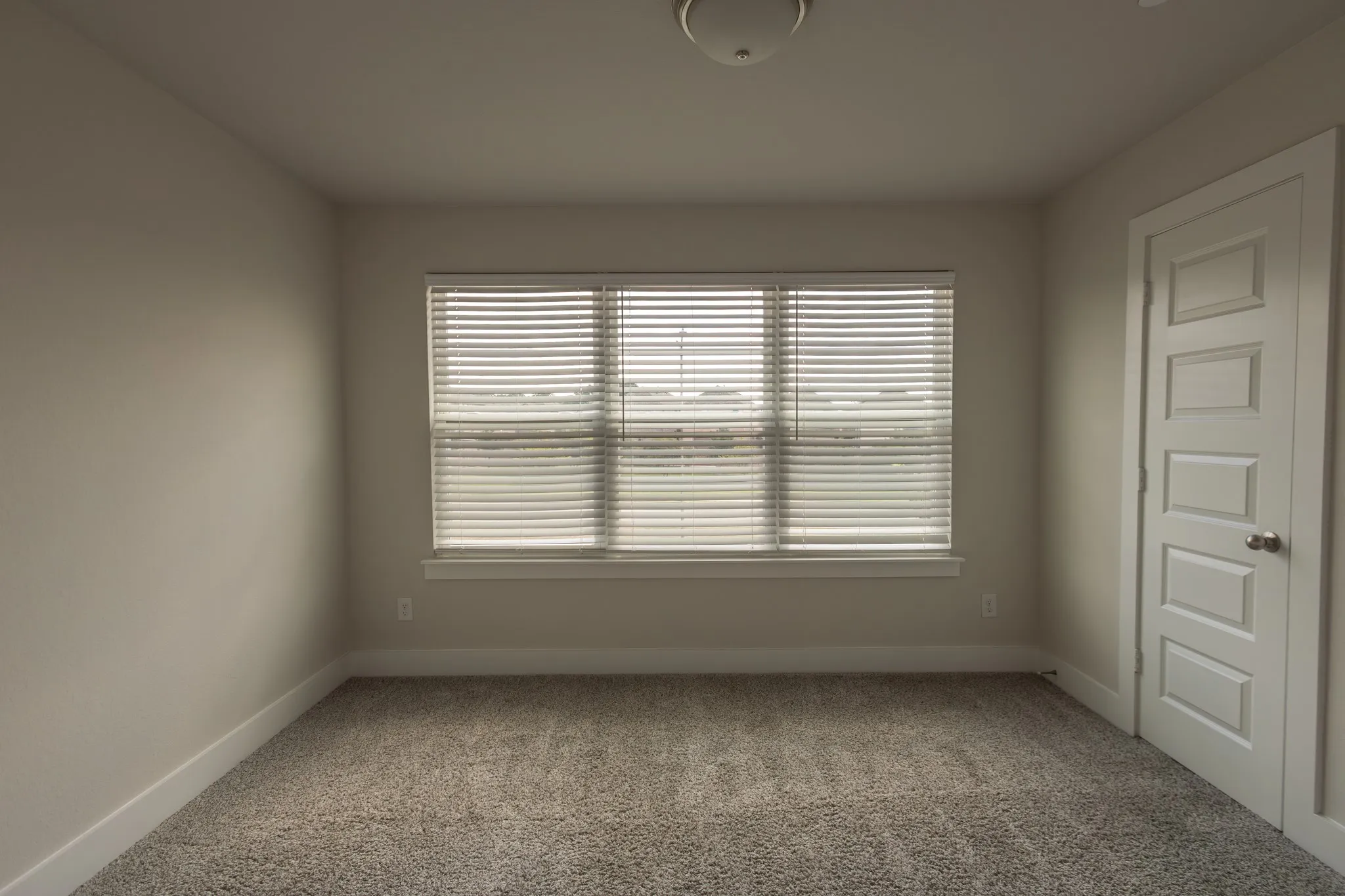 Bedroom with carpeted flooring, three windows with blinds, a ceiling-mounted light fixture, and white baseboards